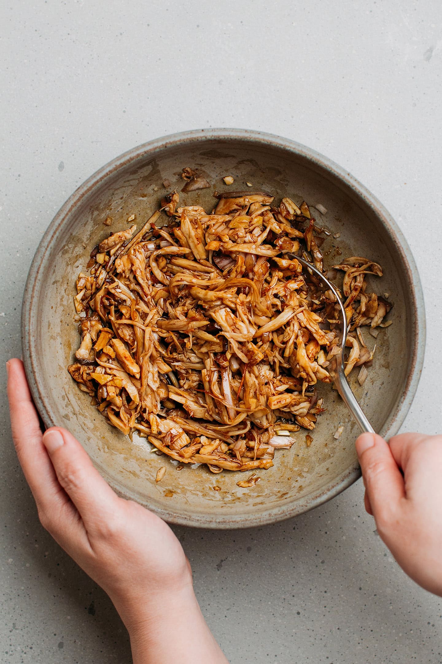 Tossing pulled king oyster mushrooms with five-spice sauce.