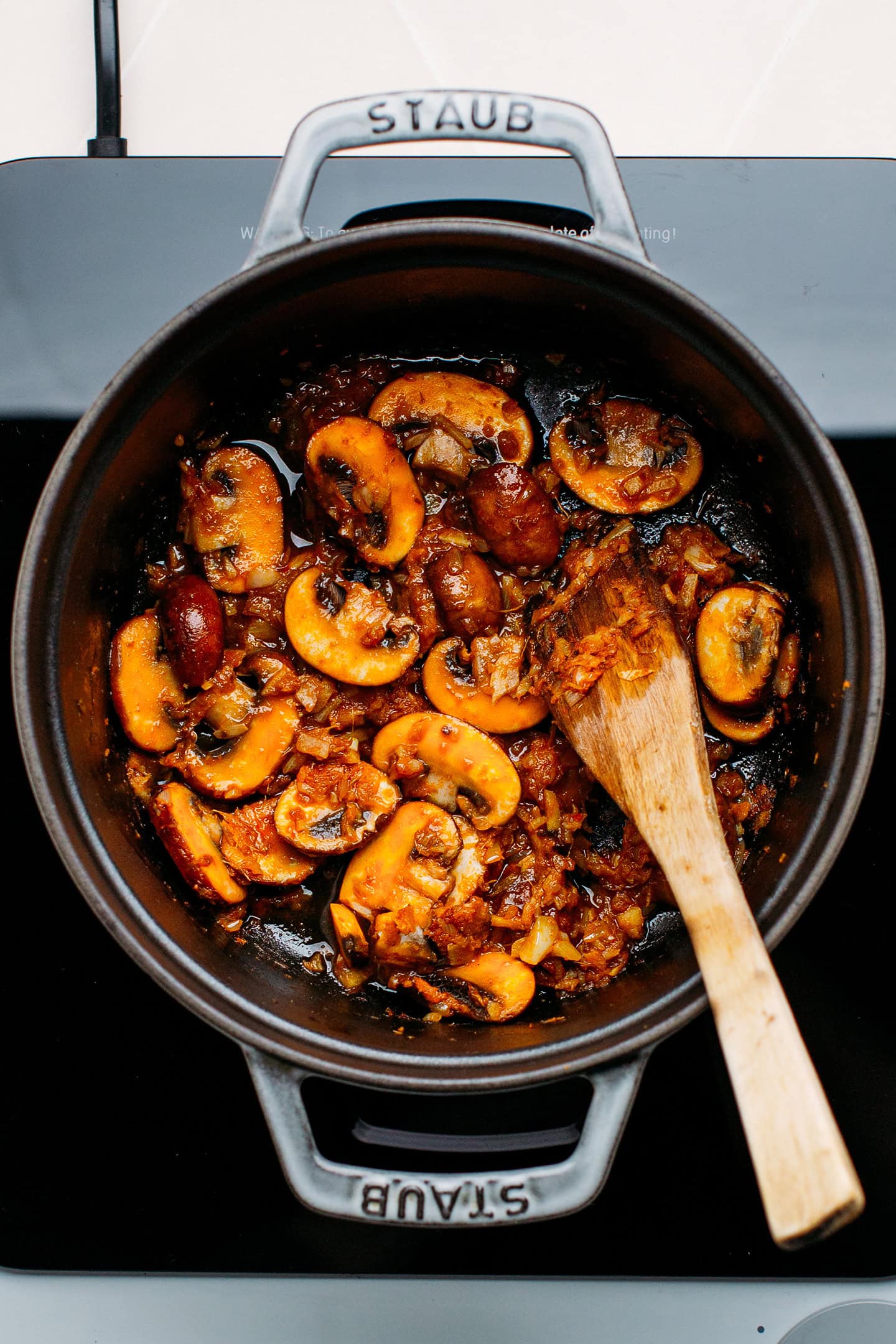 Sautéed mushrooms with red curry paste in a pot.