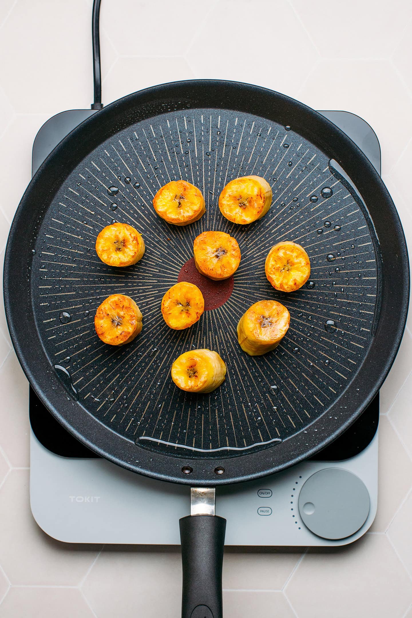 Golden brown sliced plantains on a skillet.