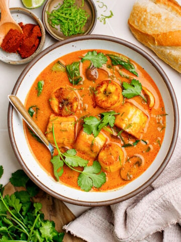 Red curry with plantains, mushrooms, and bok choy in a bowl.