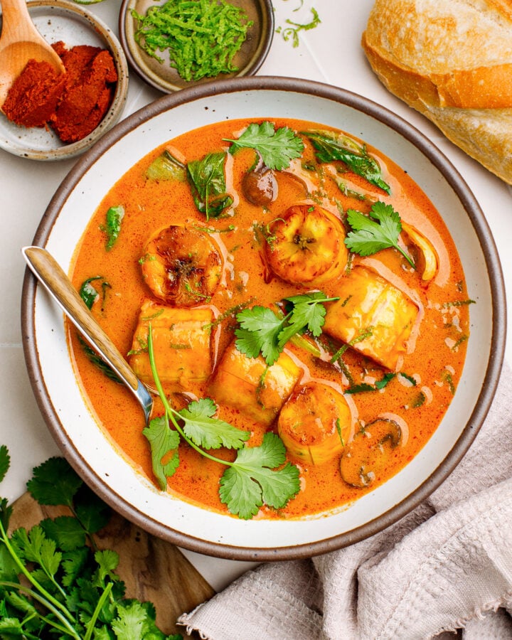 Red curry with plantains, mushrooms, and bok choy in a bowl.