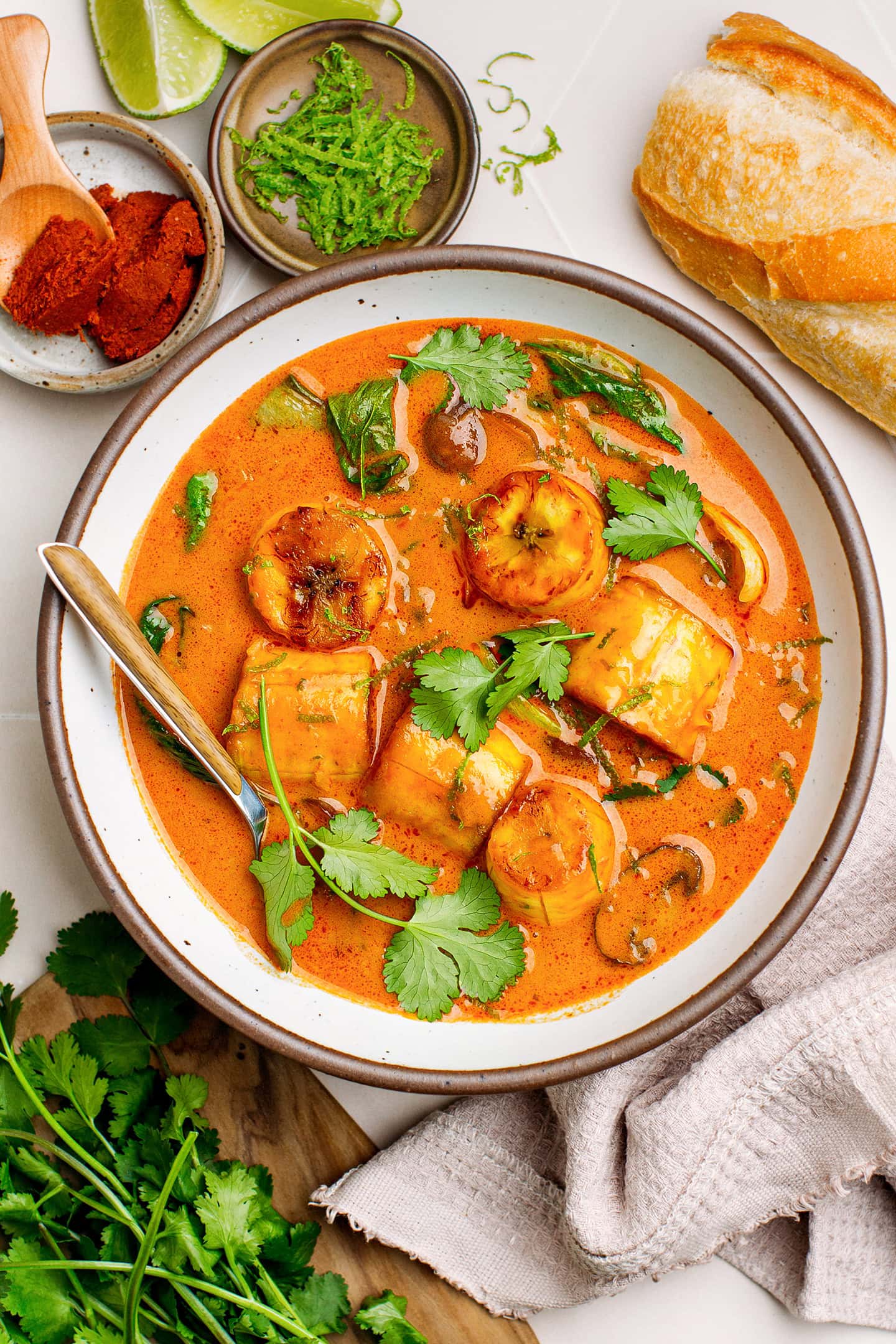 Red curry with plantains, mushrooms, and bok choy in a bowl.