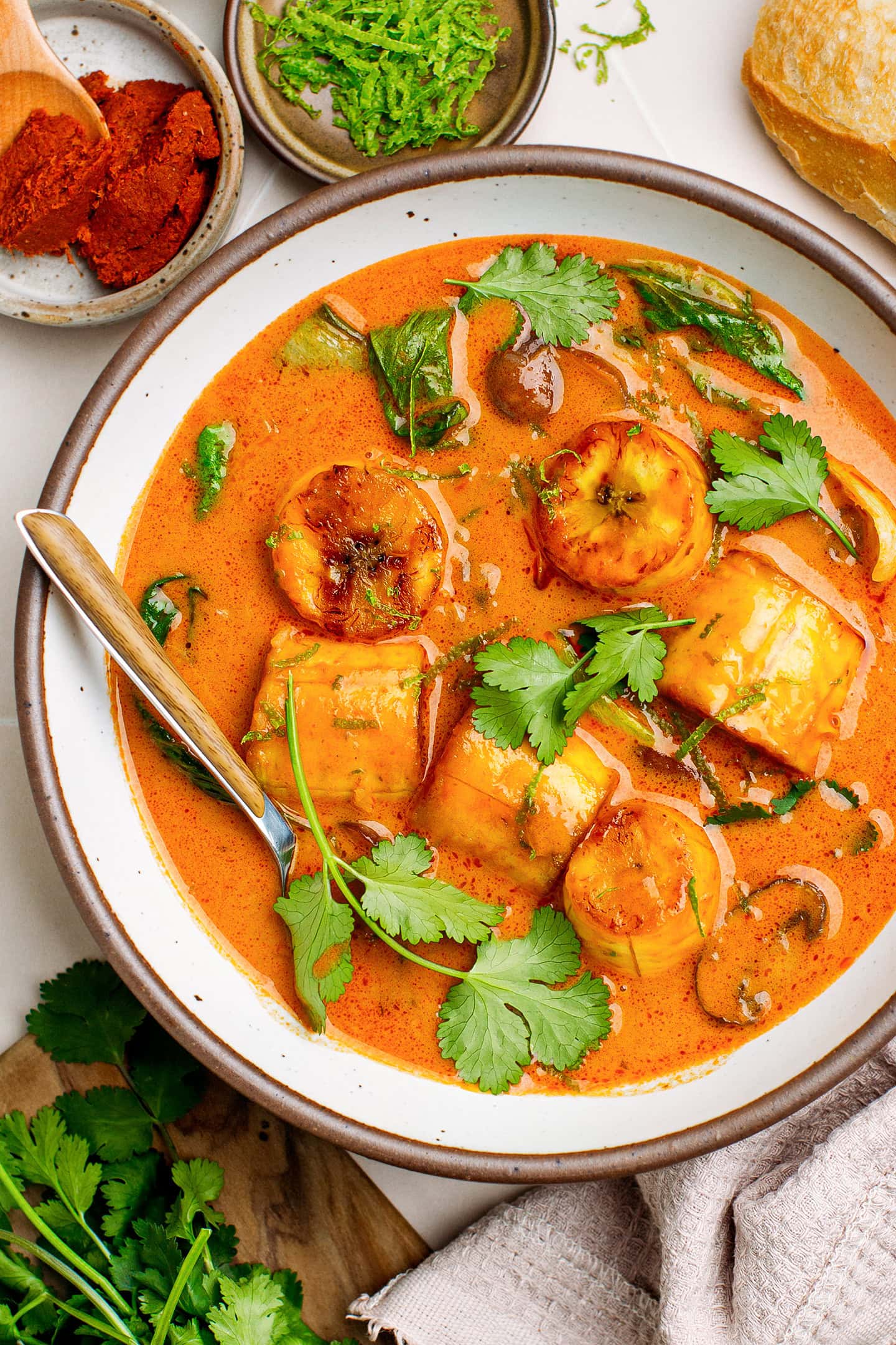 Bowl of red curry with plantains, mushrooms, and cilantro.