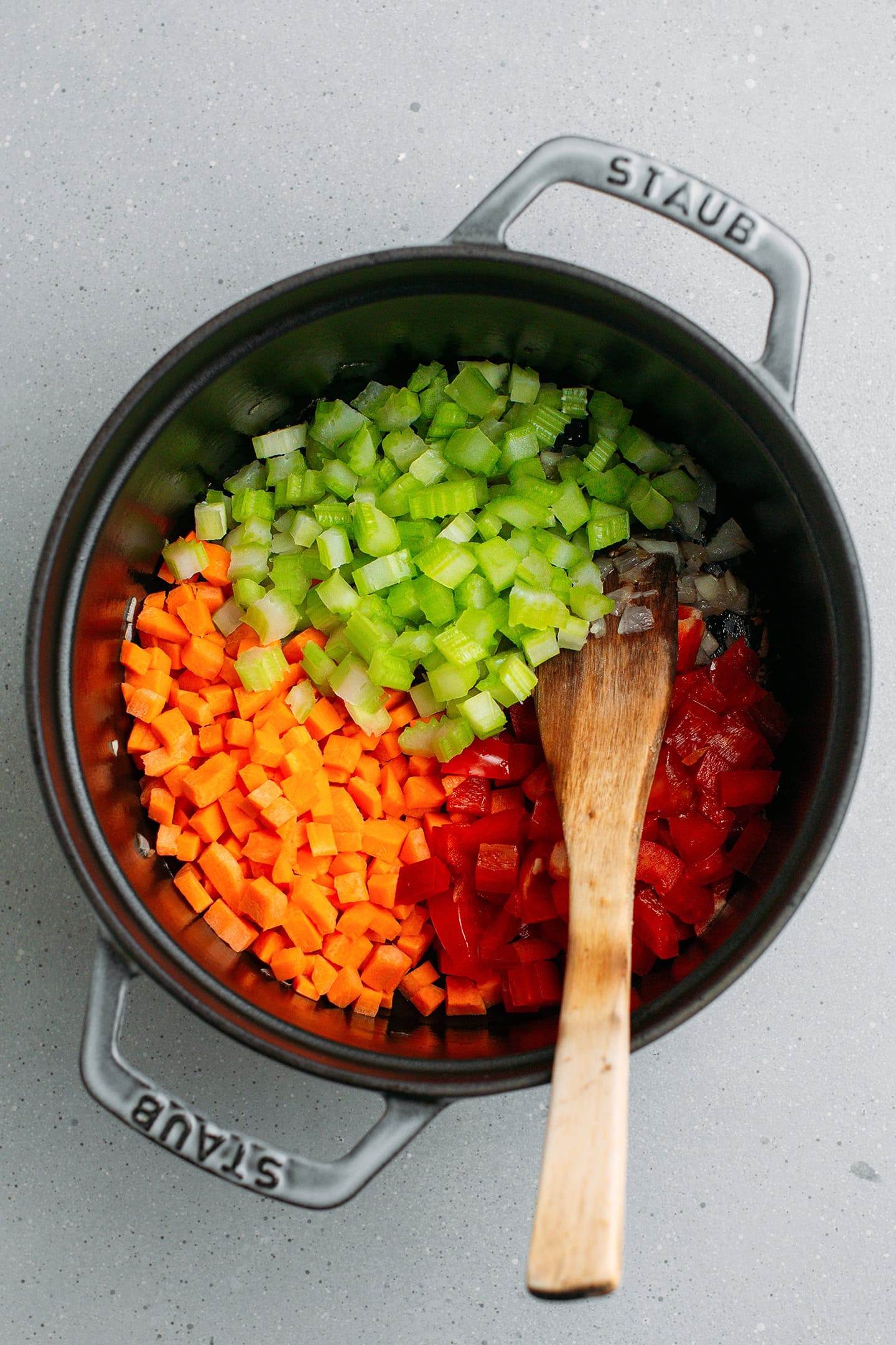 Diced carrots, celery, and red bell pepper in a pot.
