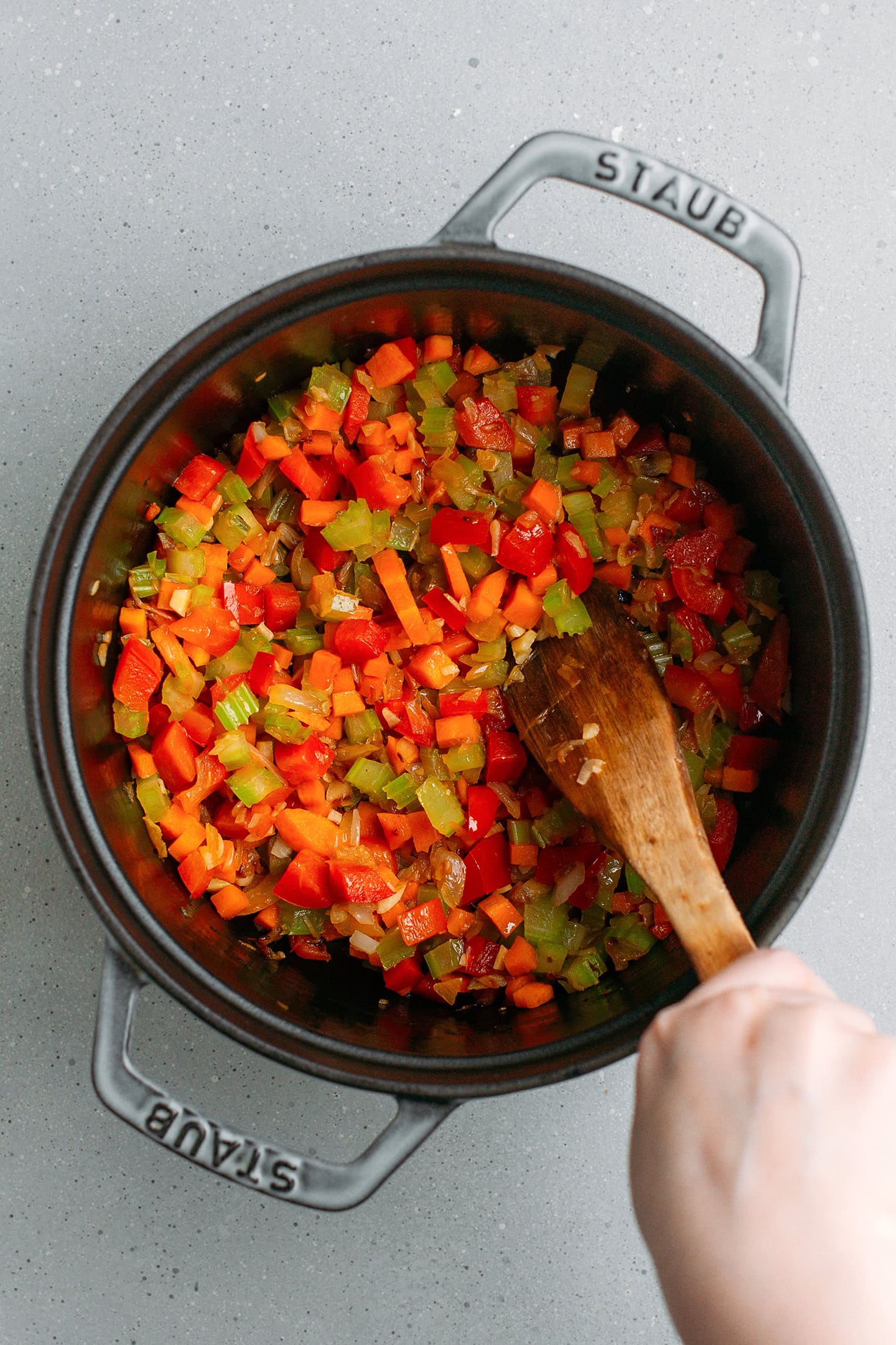 Sautéed carrots, celery, and bell peppers in a pot.