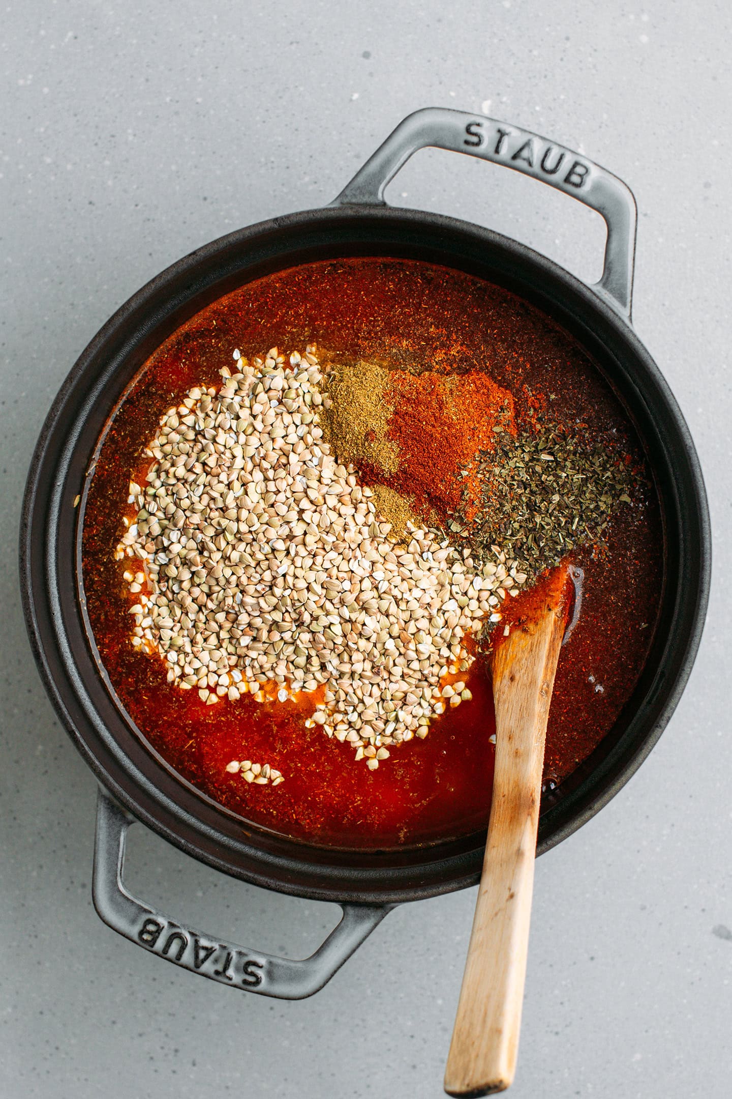 Diced tomatoes, aromatics, and buckwheat groats in a pot.