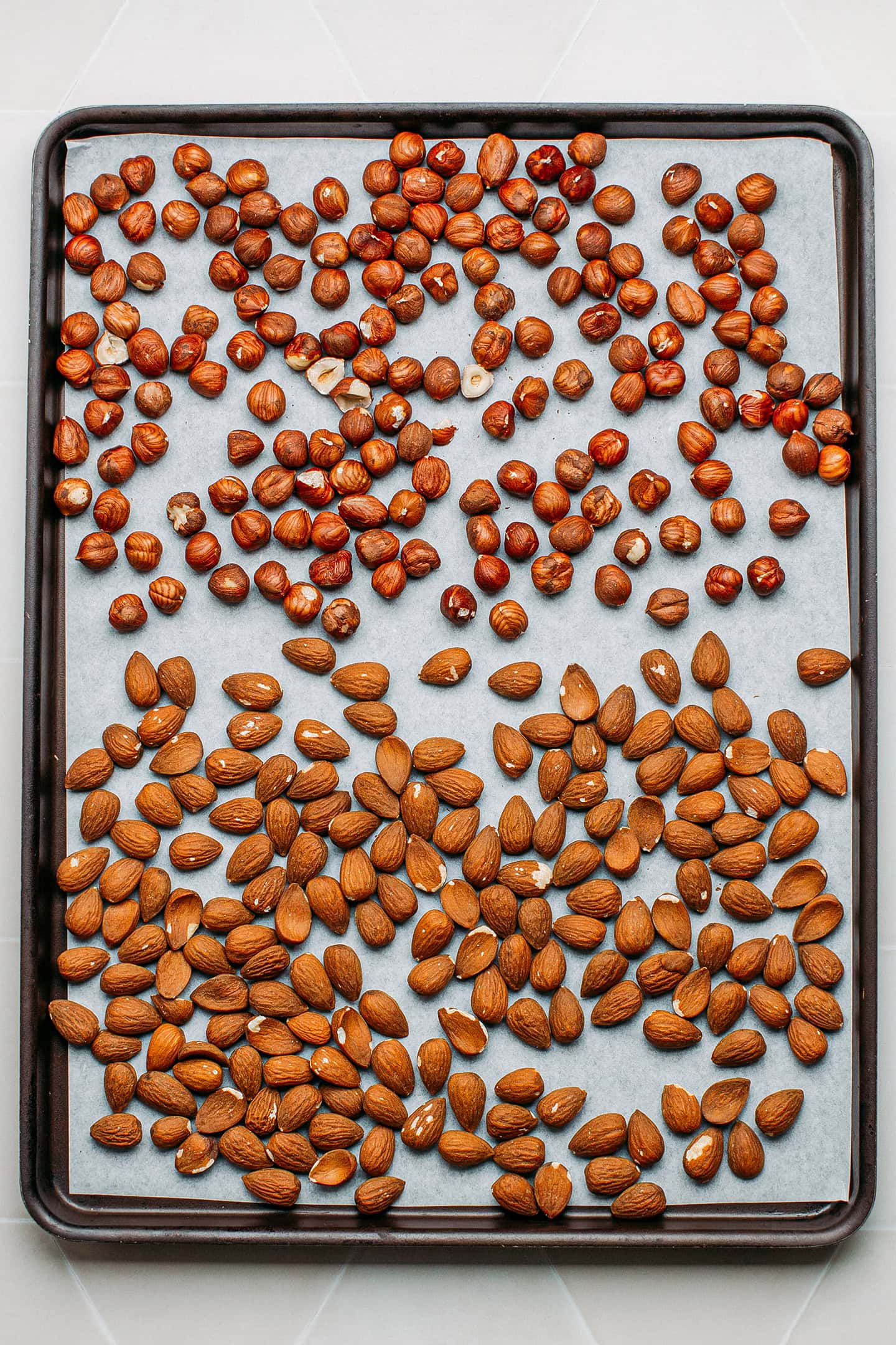 Almonds and hazelnuts on a baking sheet.