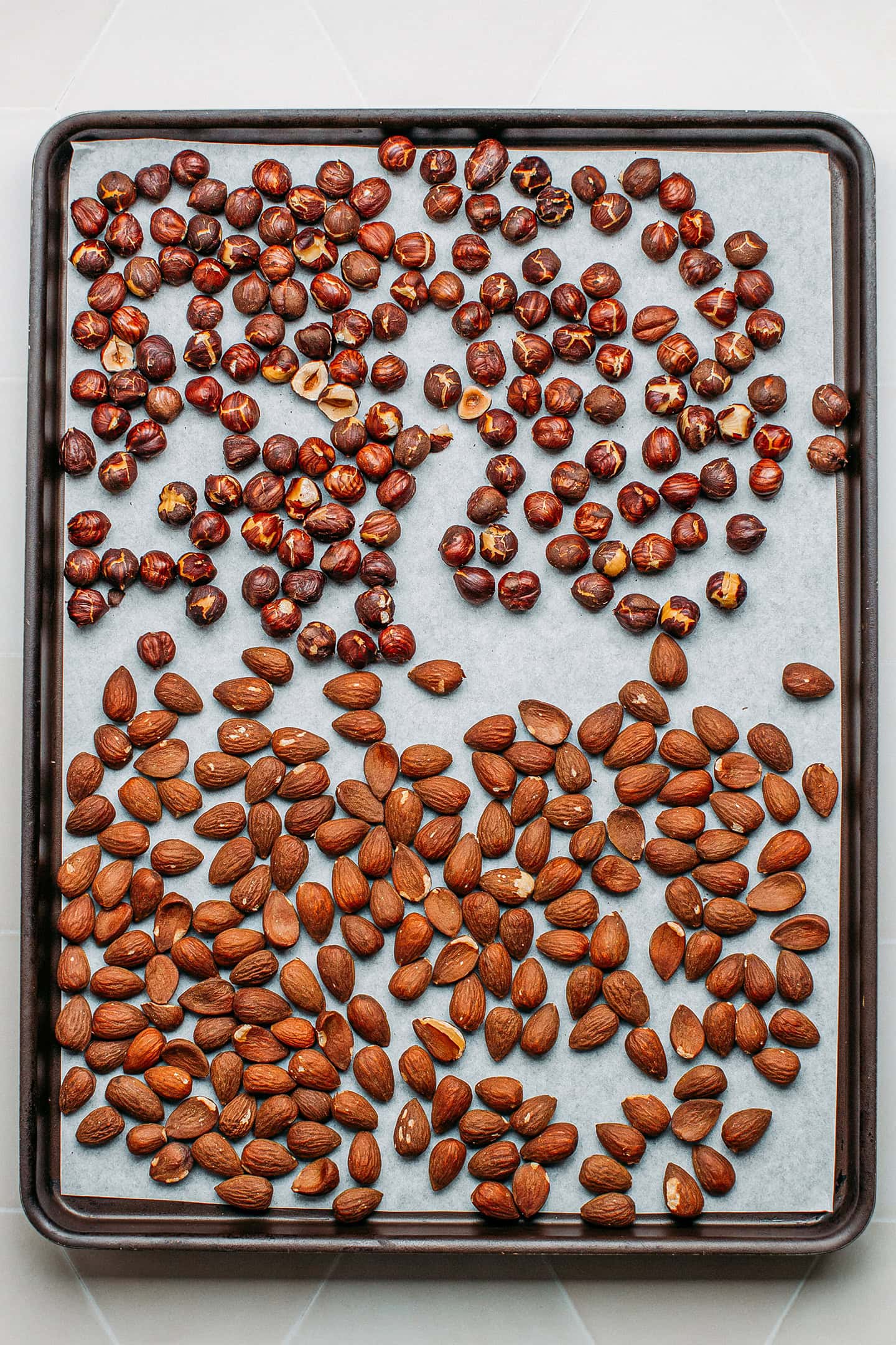 Roasted almonds and hazelnuts on a baking sheet.