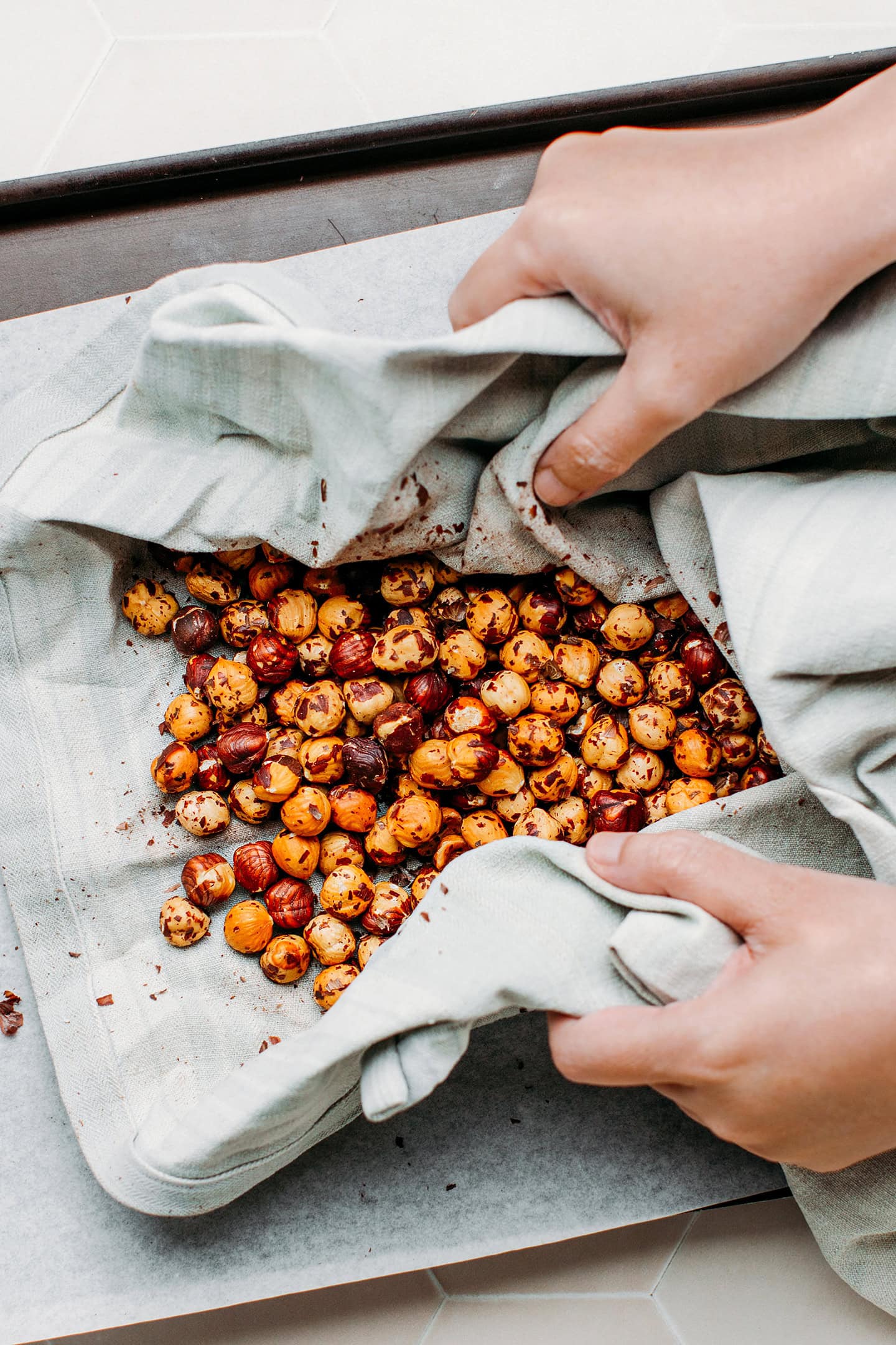 Rubbing roasted hazelnuts with a kitchen towel.