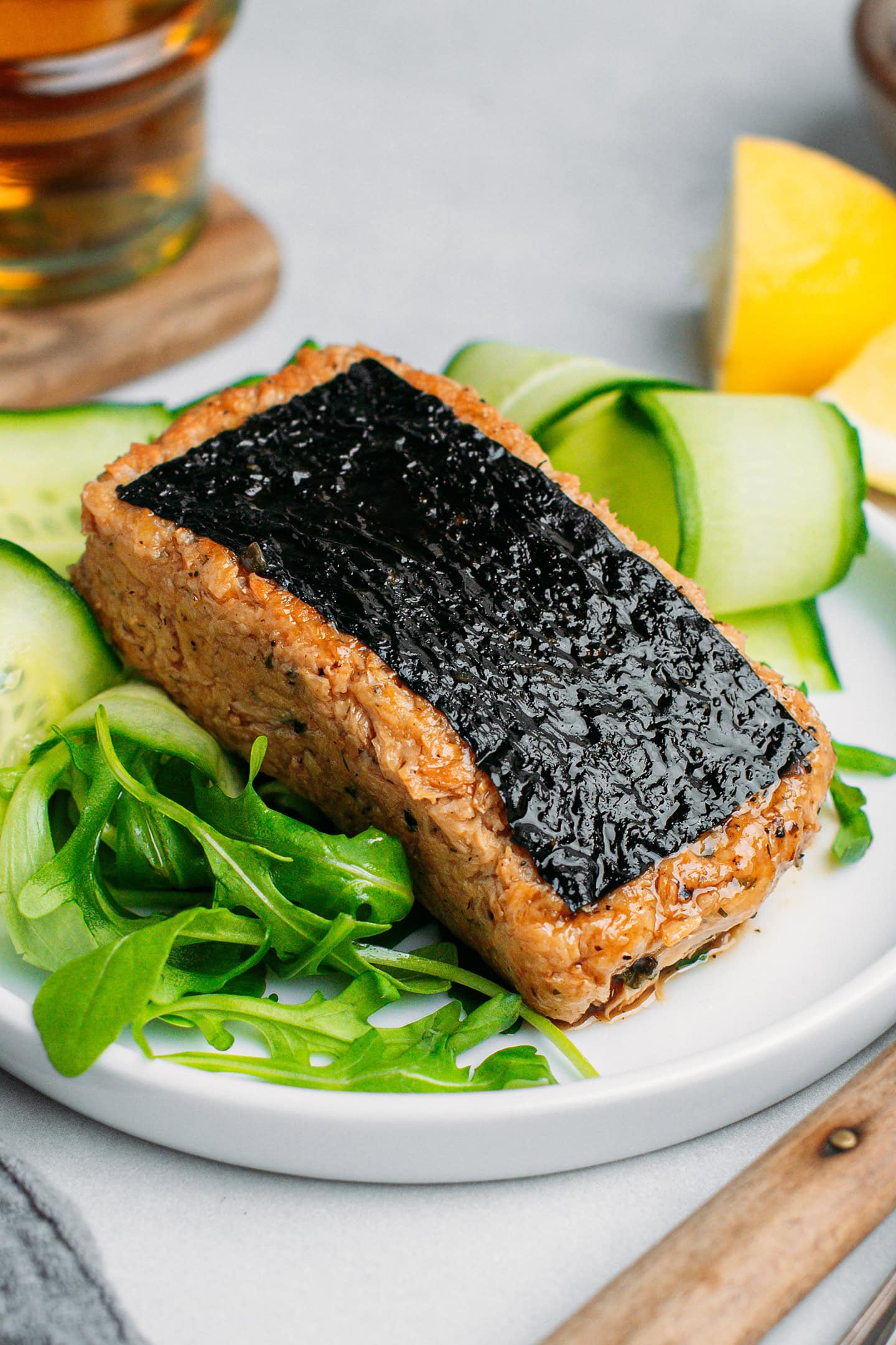 Vegan fish filled on a plate filled with arugula and sliced cucumber.