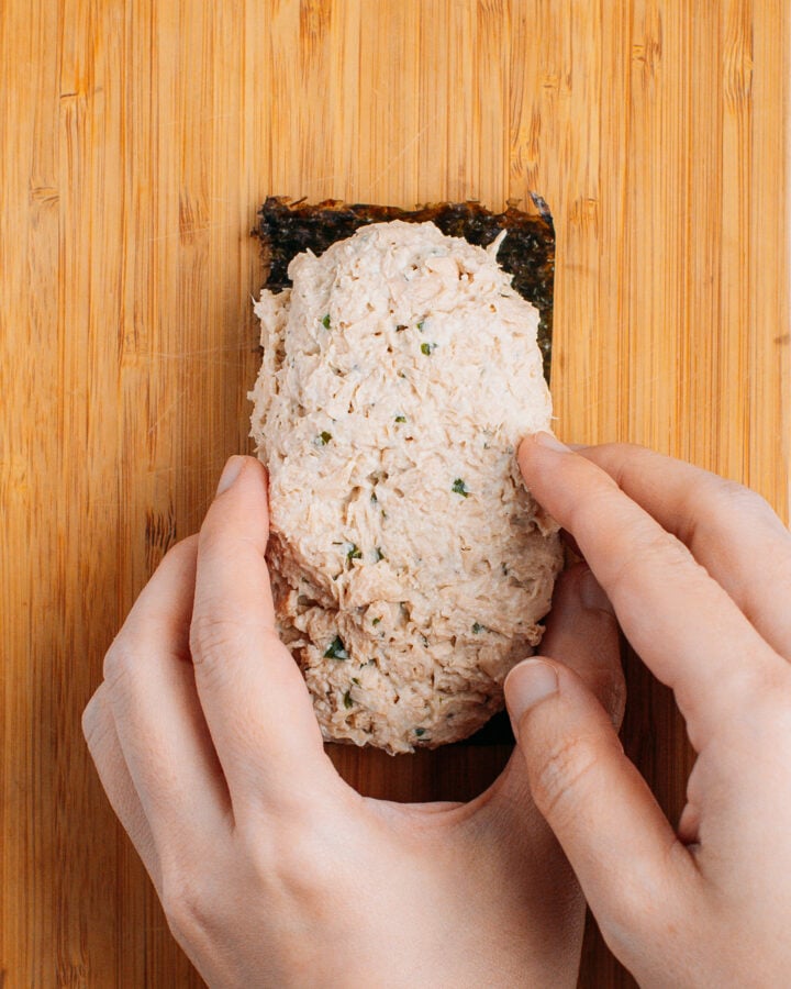 Arranging tofu mixture over a sheet of nori.
