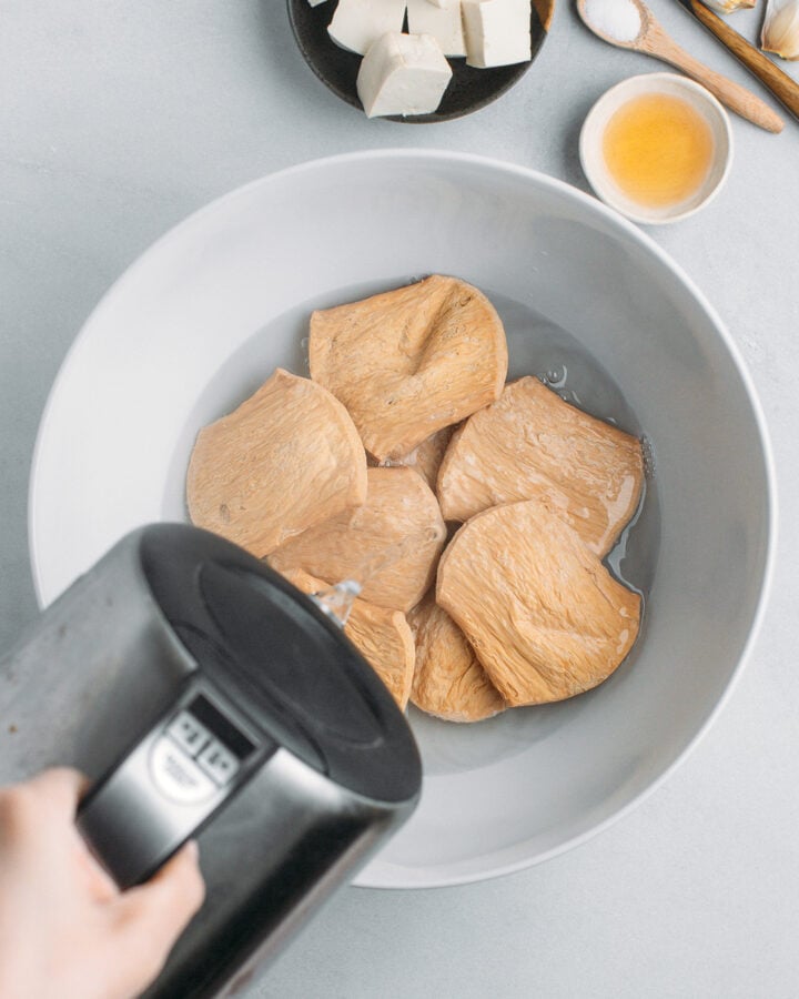 Pouring boiling water into a bowl containing TVP slices.