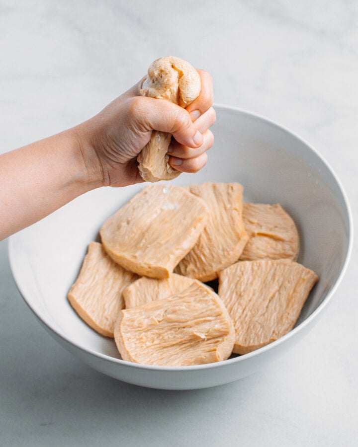 Squeezing TVP slices over a bowl.
