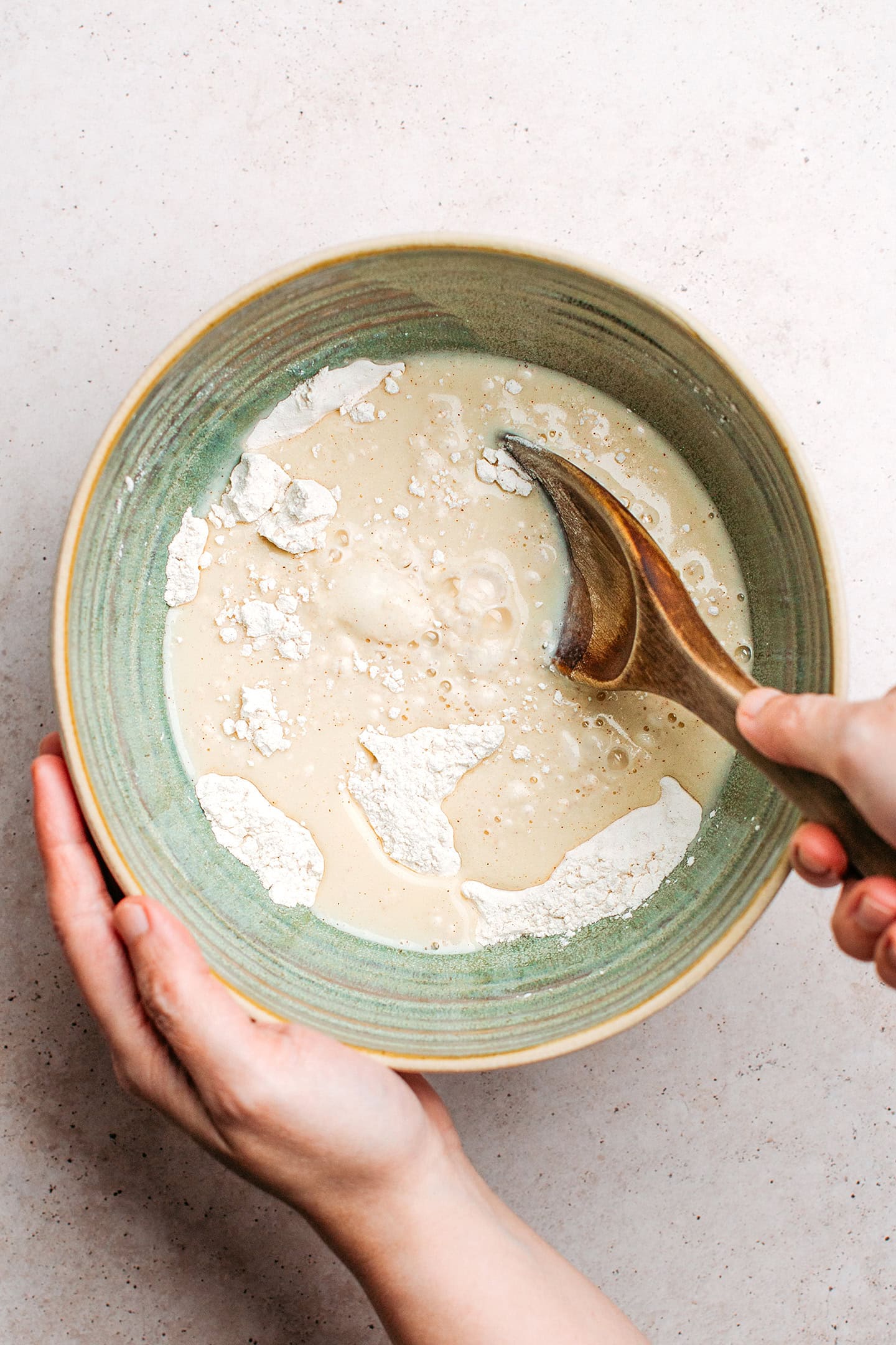 Whisking flour with milk and sugar in a mixing bowl.