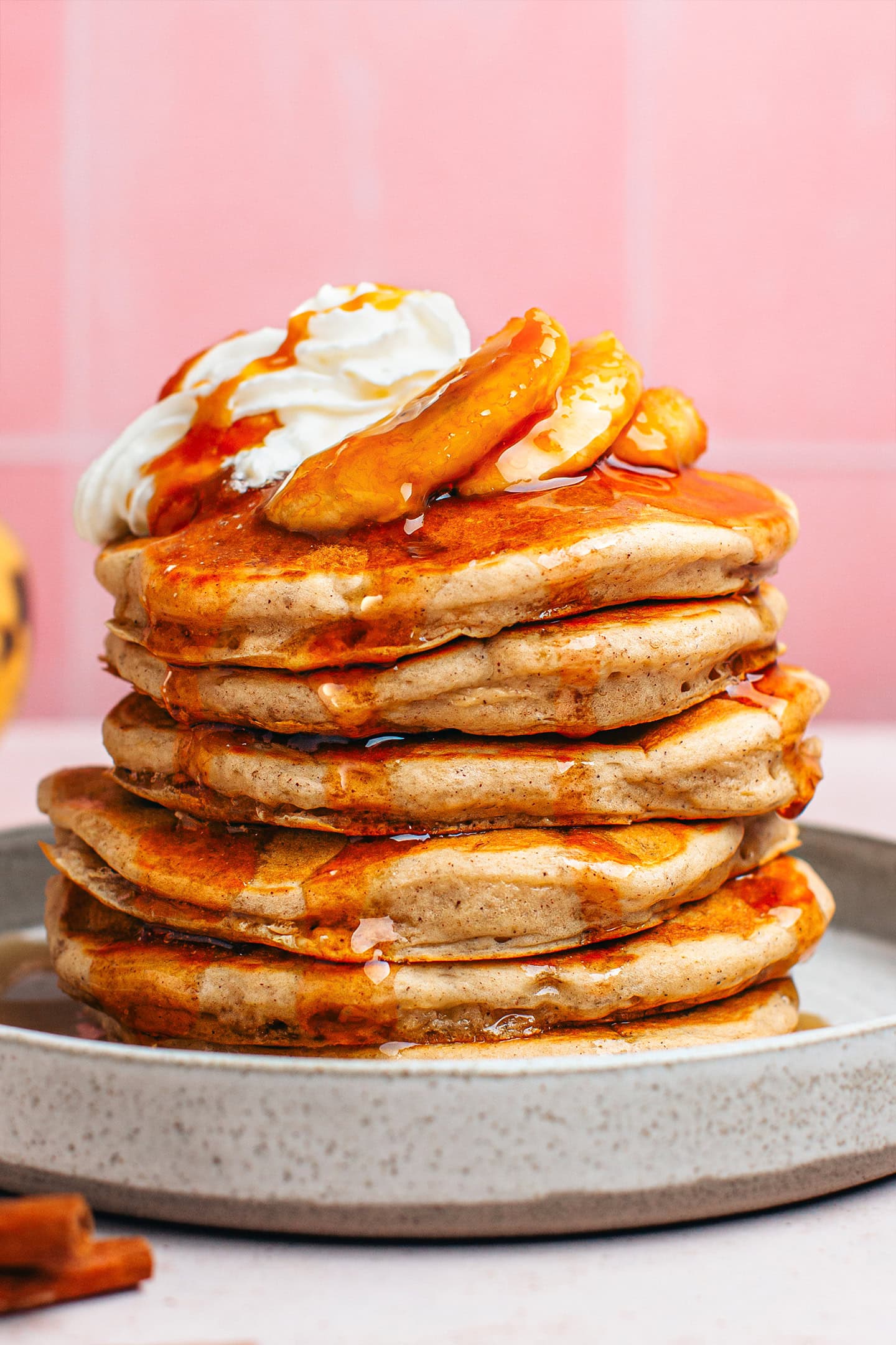 Stack of banana pancakes topped with whipped cream and caramelized bananas.