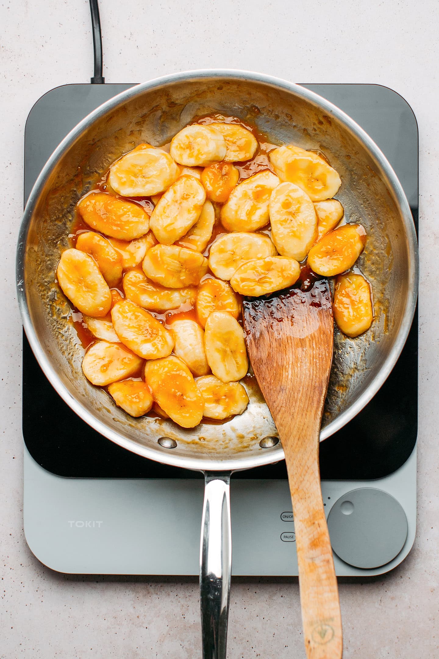 Banana slices coated with caramel in a skillet.