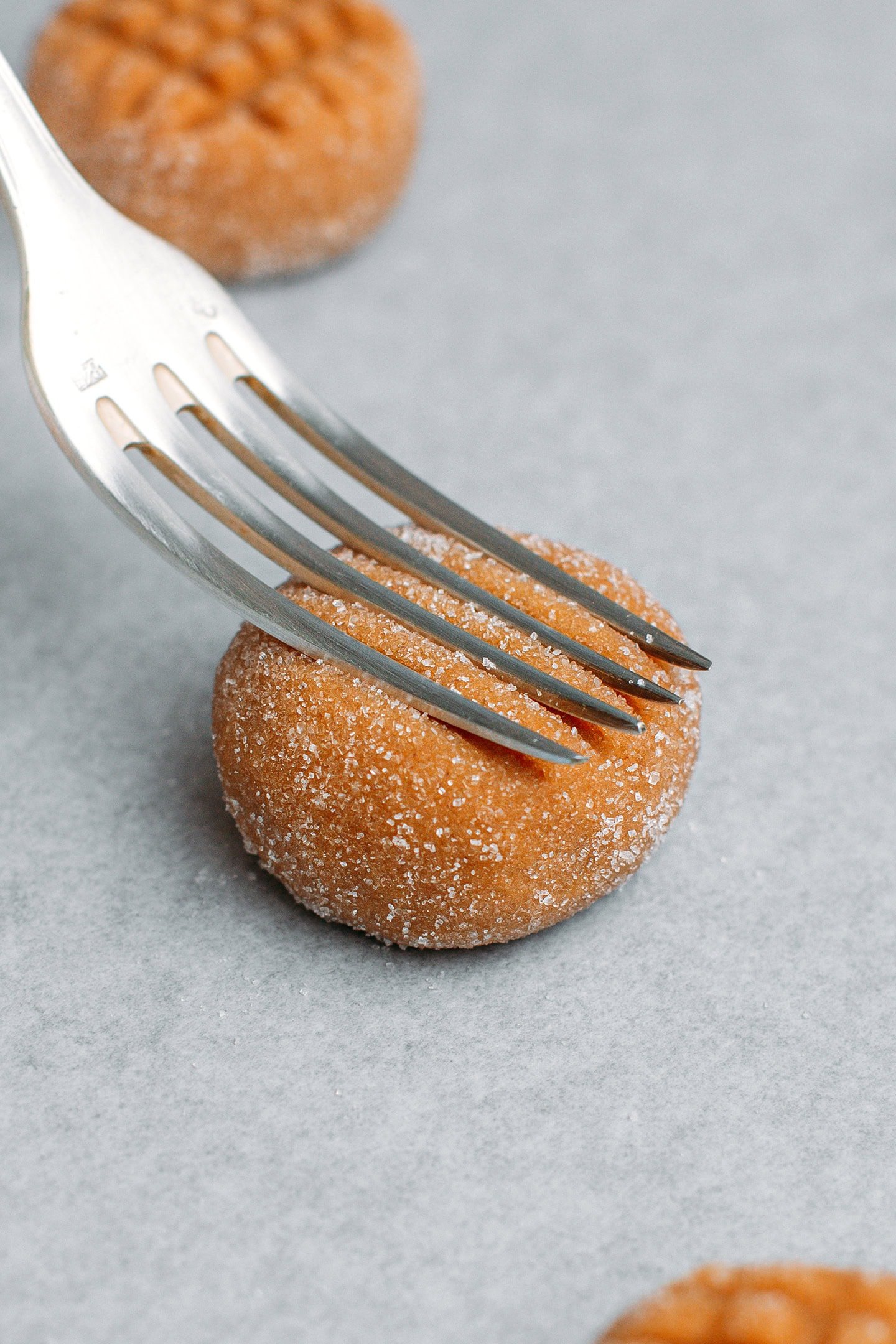 Pressing a fork on an unbaked peanut butter cookie.