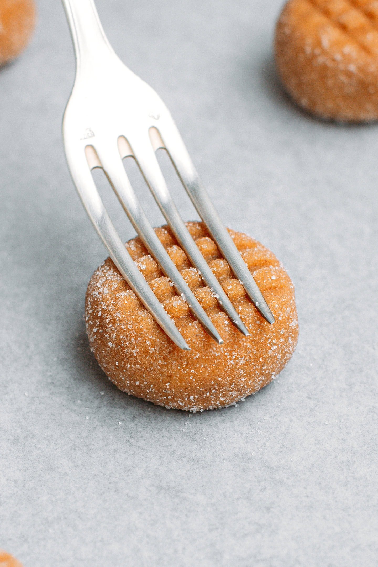 Pressing a fork on a ball of peanut butter cookie dough.