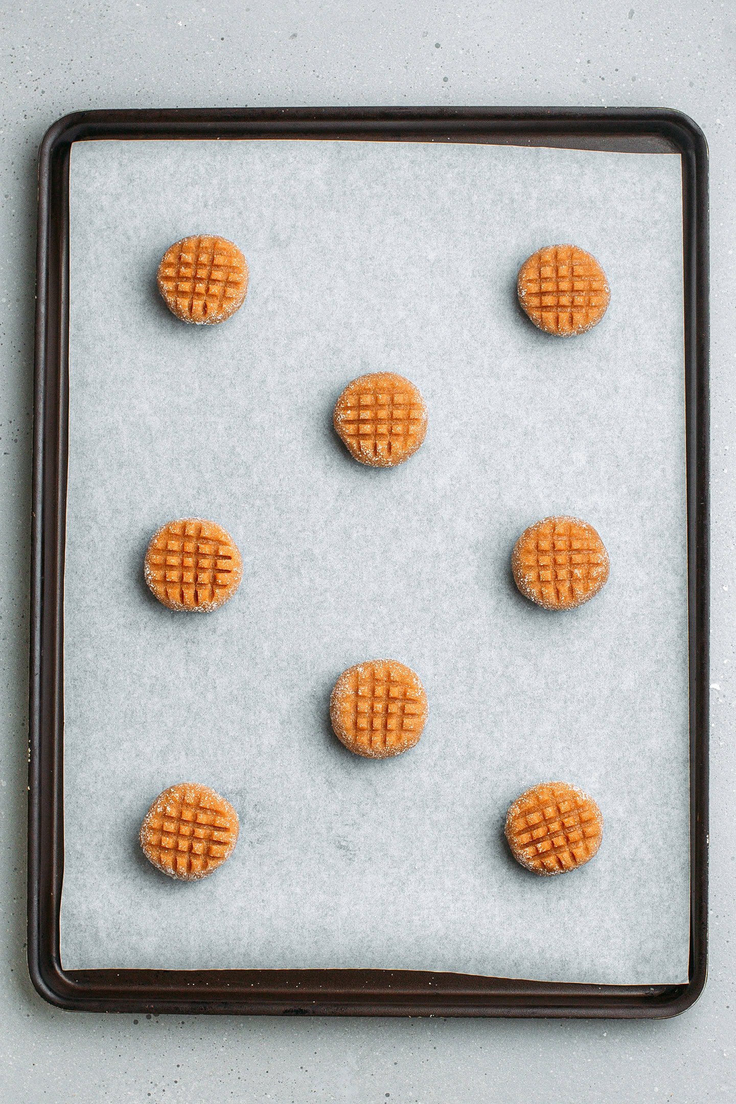Unbaked peanut butter cookies on a baking sheet.