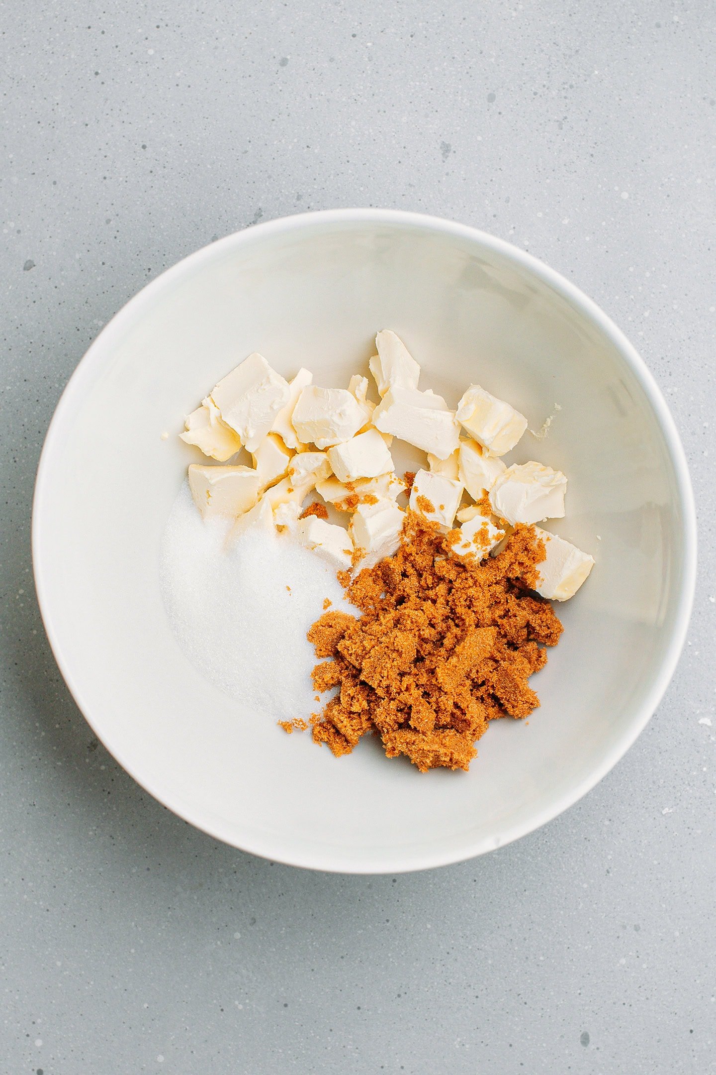 Diced butter, granulated sugar, and brown sugar in a mixing bowl.