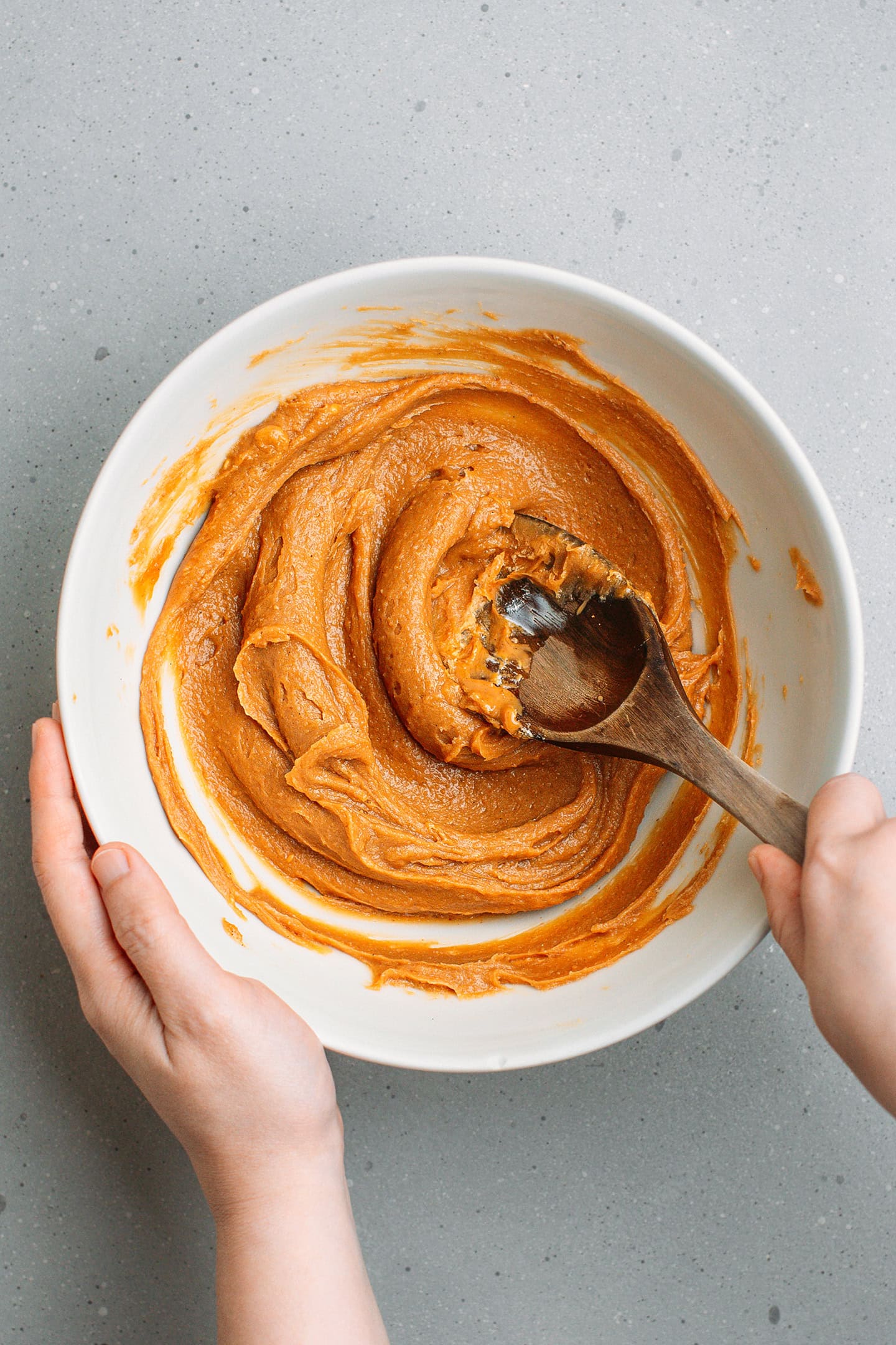 Mixing peanut butter with creamed butter in a mixing bowl.