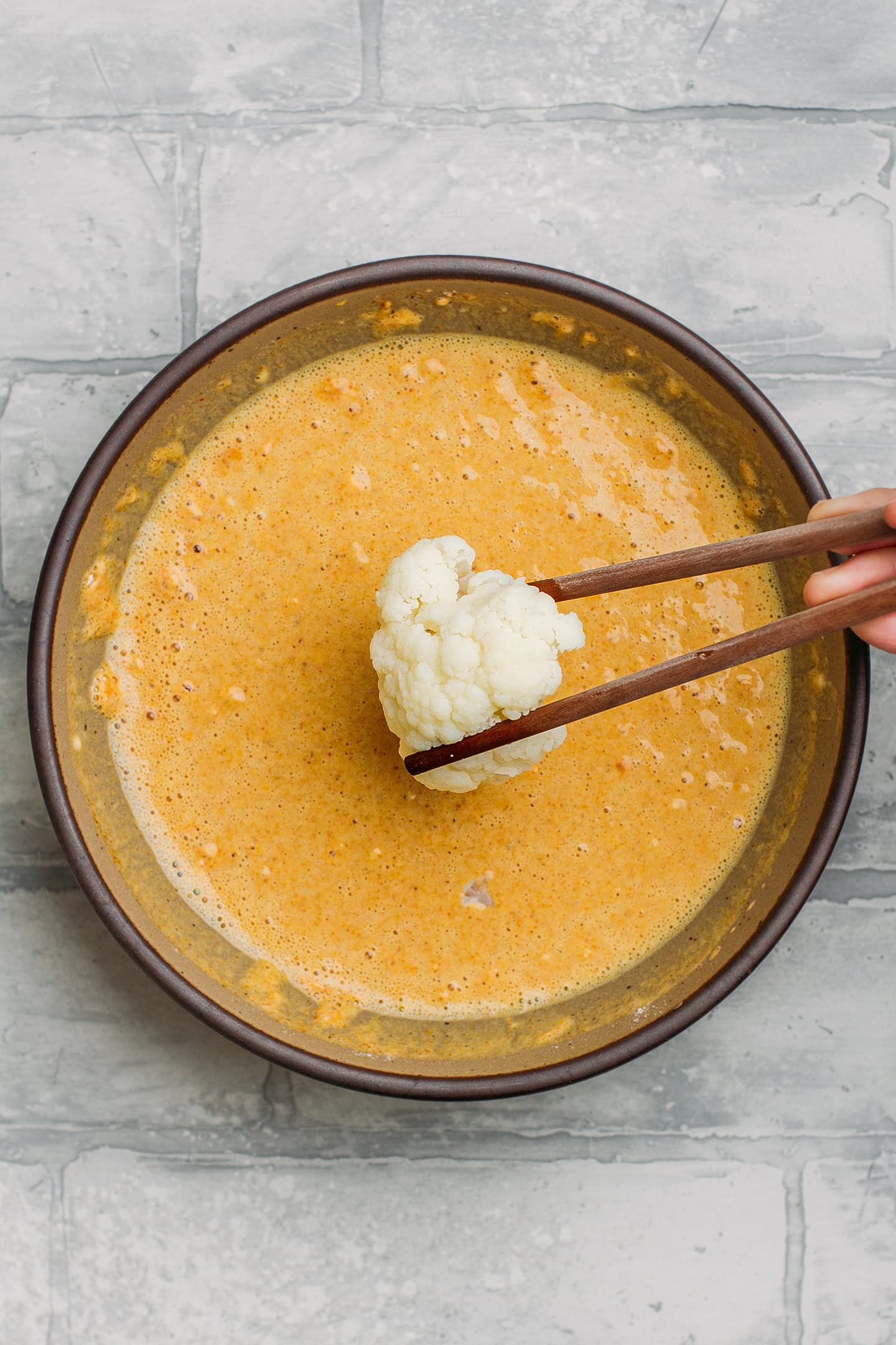 Dipping a cauliflower floret into a batter.