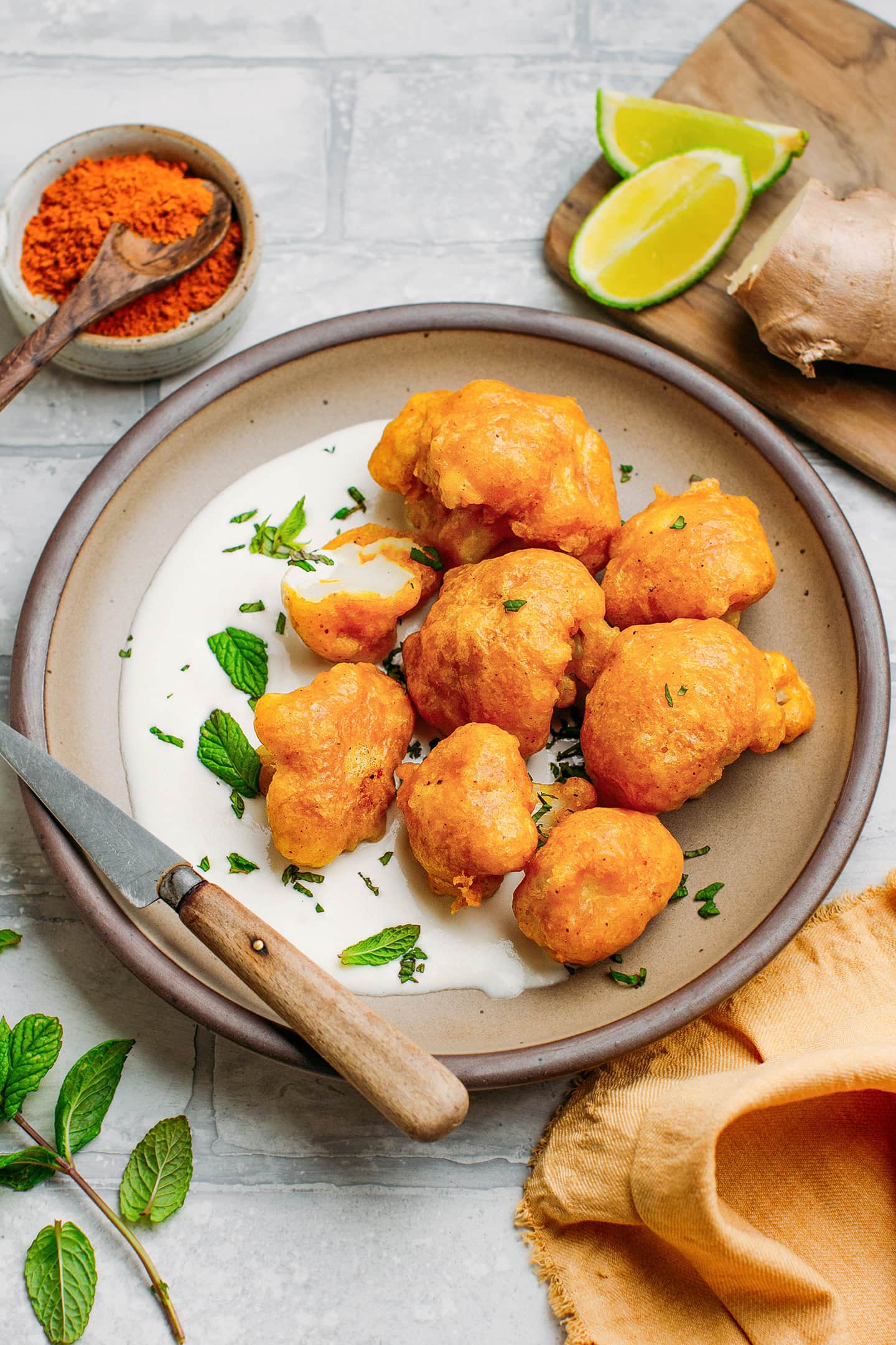 Cauliflower tempura with cashew ginger sauce and mint leaves on a plate.