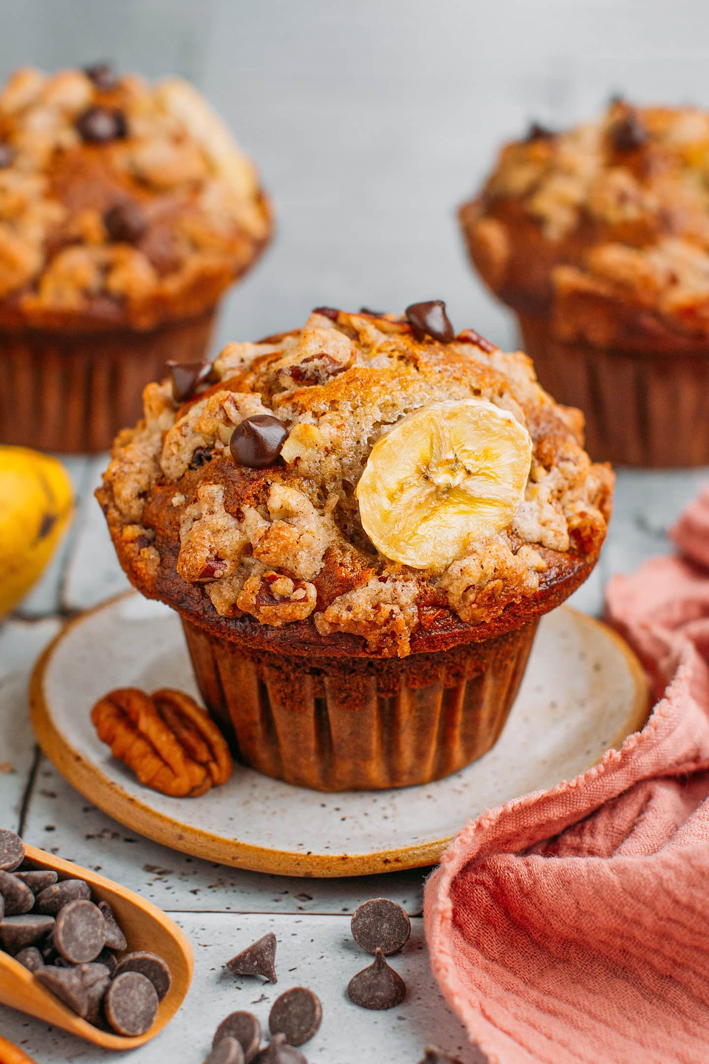 Banana muffin topped with chocolate chips on a small plate.