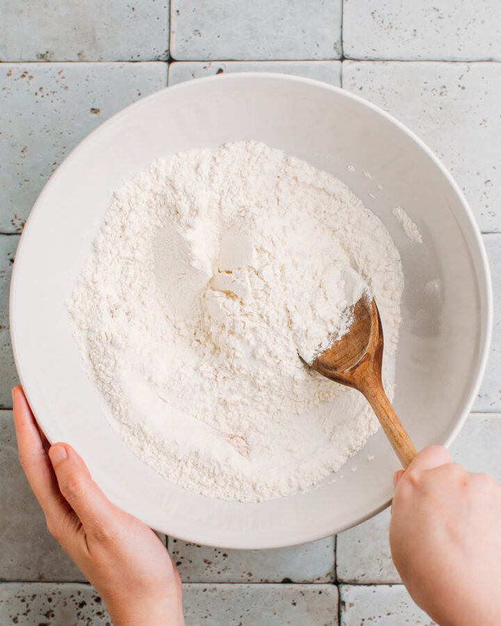 Mixing flour, sugar, and baking powder in a mixing bowl.