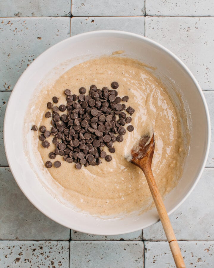 Chocolate chips on top of a muffin batter in a bowl.