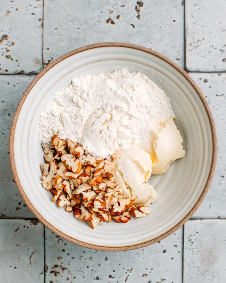 Chopped pecans, flour, sugar, and butter in a bowl.