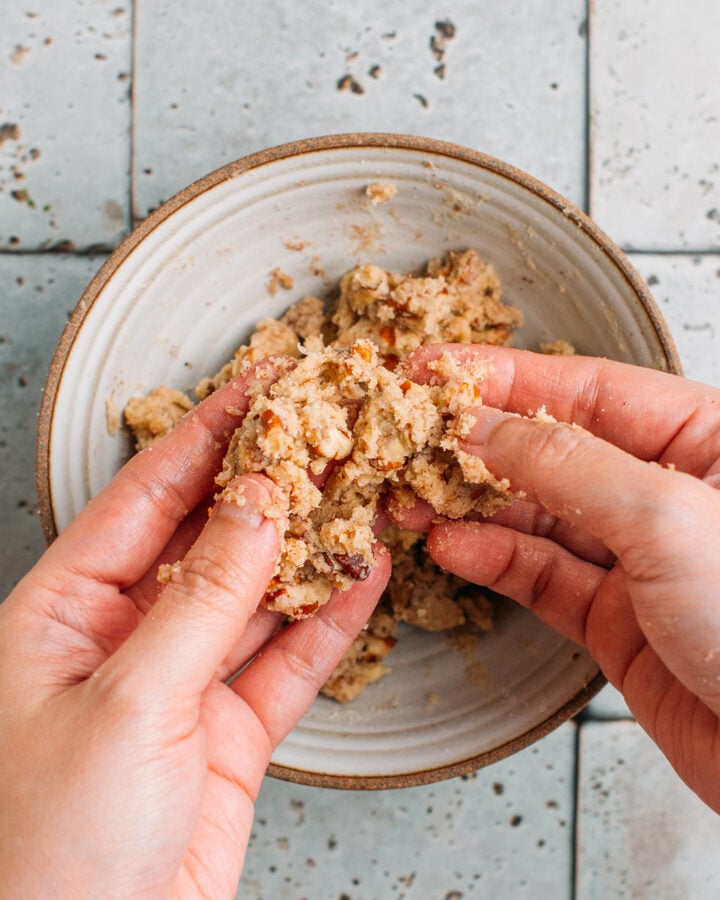 Making a streusel topping with pecans, flour, and sugar in a bowl.