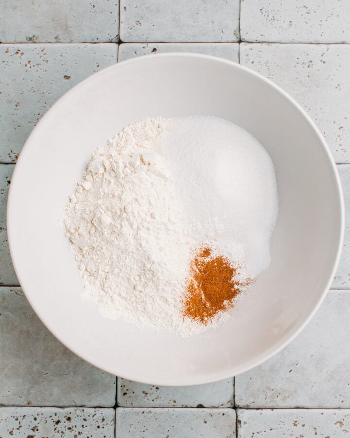 Flour, sugar, baking powder, and cinnamon in a mixing bowl.
