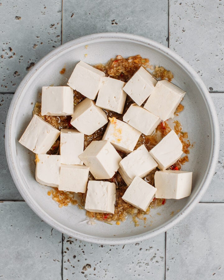 Diced tofu in a bowl on top of a lemongrass marinade.