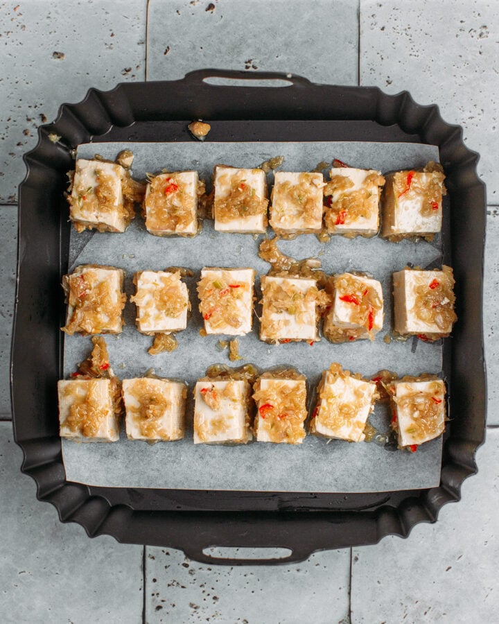 Diced tofu coated with lemongrass in an air fryer basket.