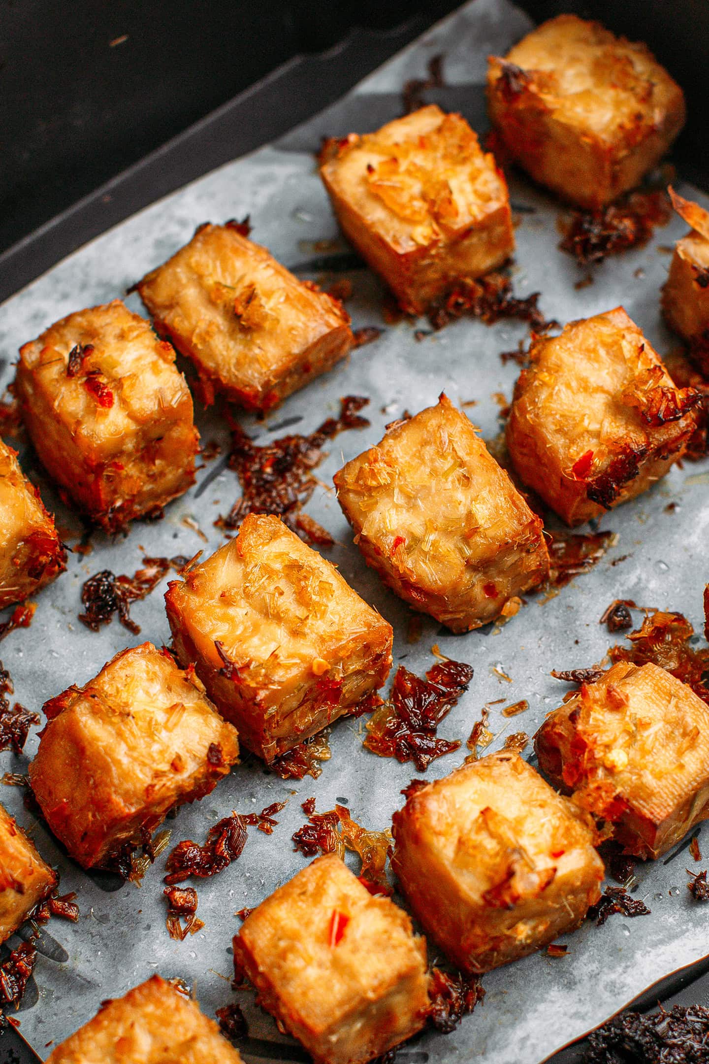 Lemongrass tofu cubes in the basket of an air fryer.