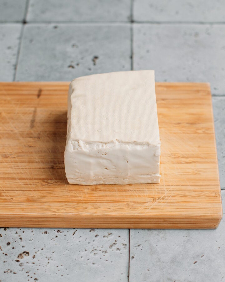 Block of tofu on a cutting board.