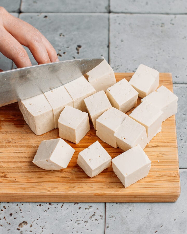 Slicing firm tofu into cubes.