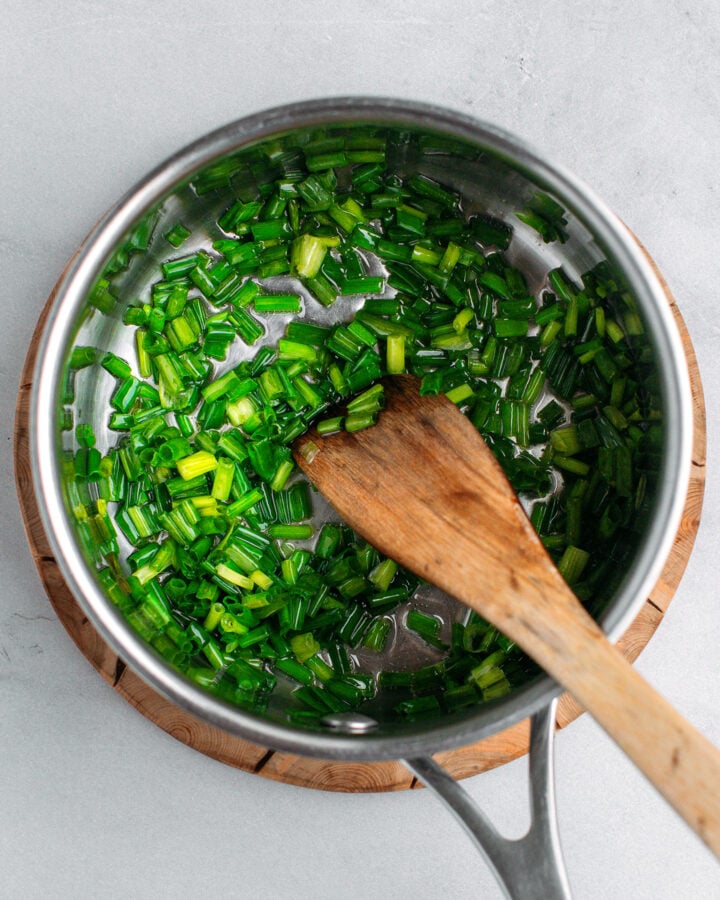 Sautéed chopped green onions in a saucepan.
