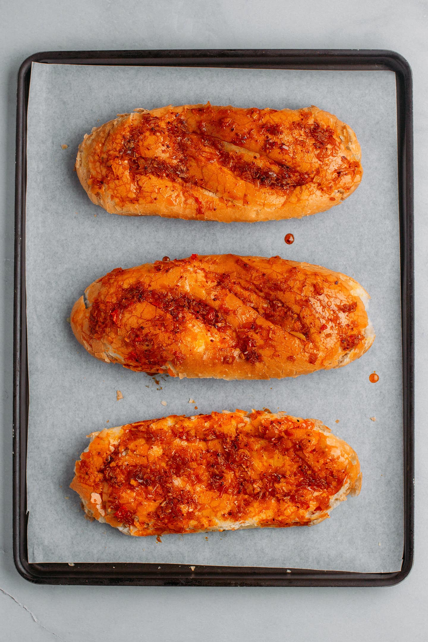 Banh mi bread coated with saté on a baking sheet.
