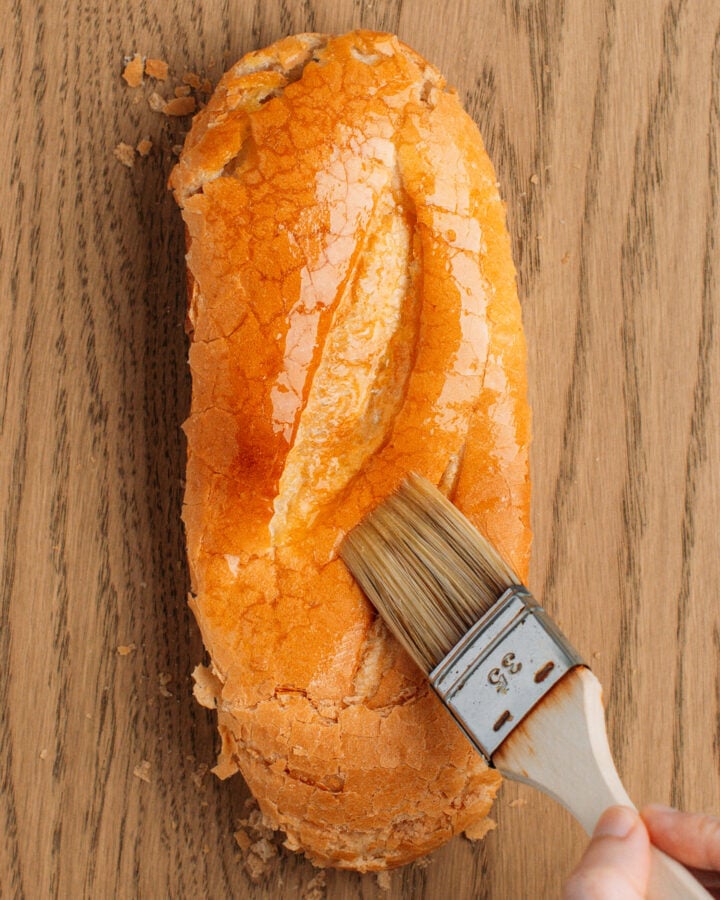 Brushing flattened bread with melted butter.