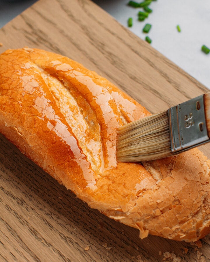 Close-up of brushing melted butter on top of bread.