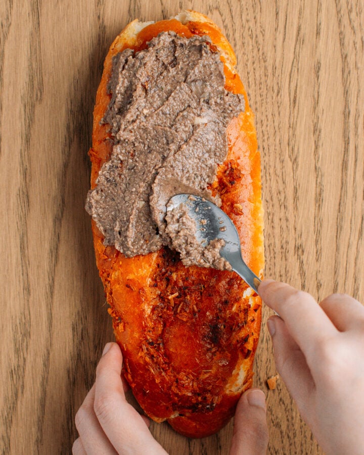 Spreading pâté on a grilled banh mi bread.