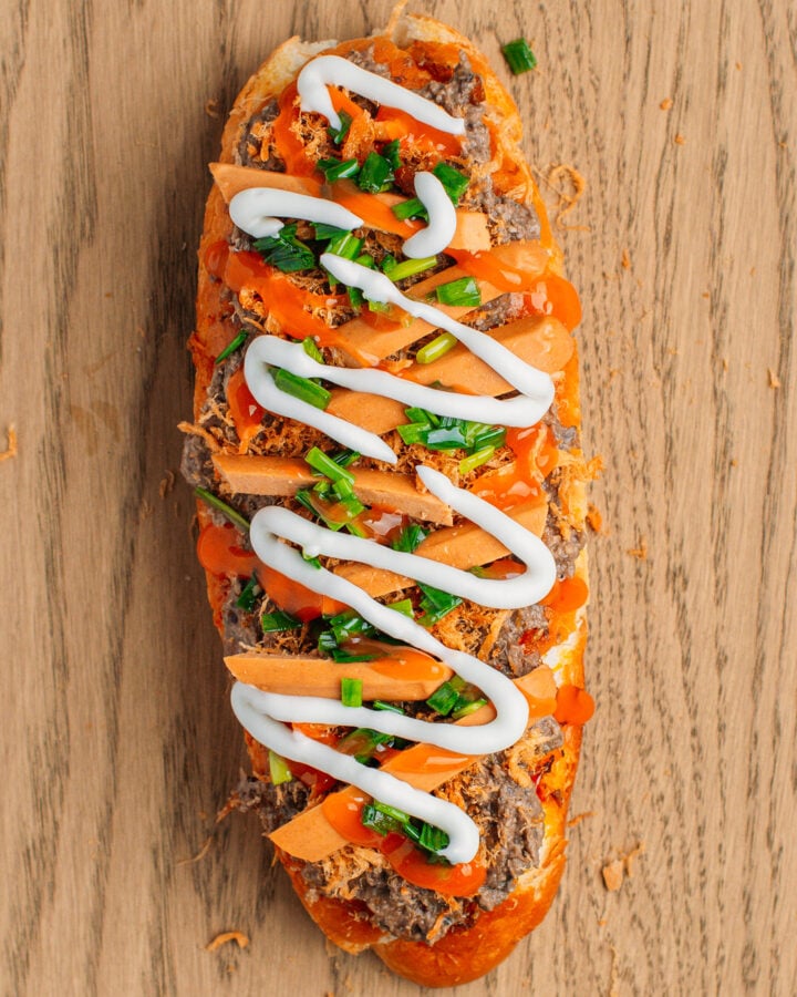 Grilled banh mi bread topped with pâté, sausages, mayo, and sweet chili sauce.