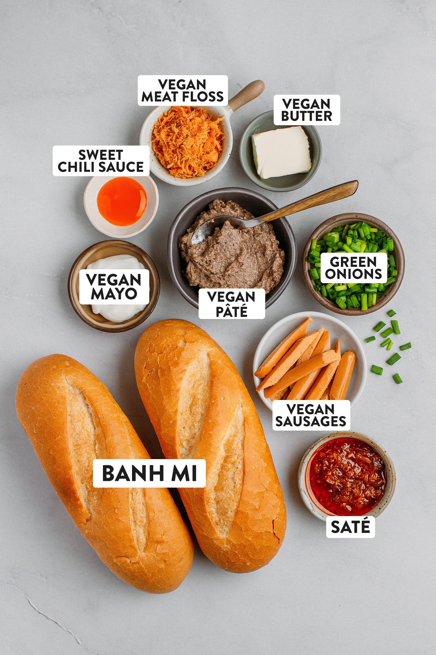 Ingredients like banh mi bread, vegan sausage, pâté, mayo, and sweet chili sauce.