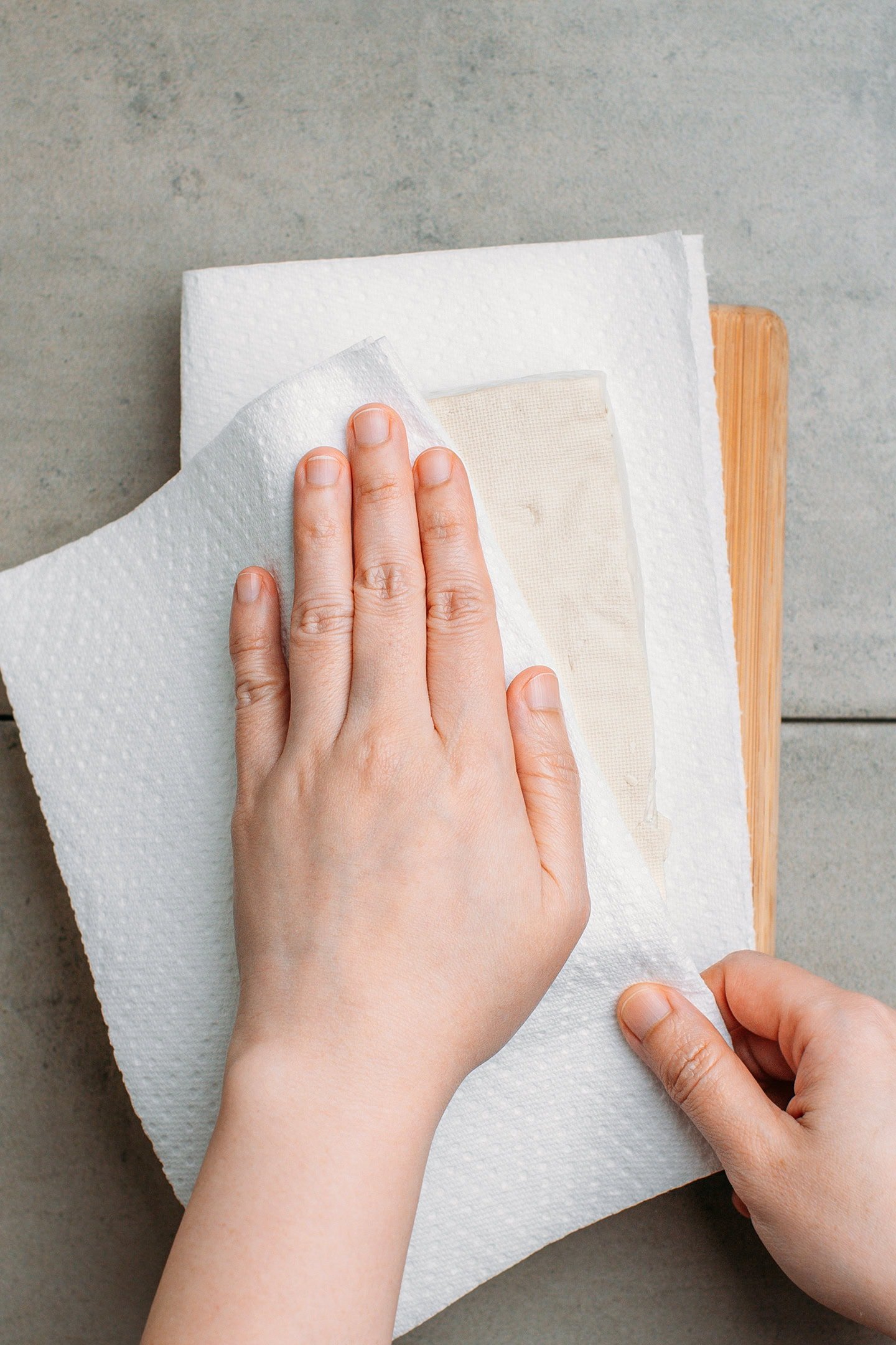 Pressing tofu with kitchen paper towels.