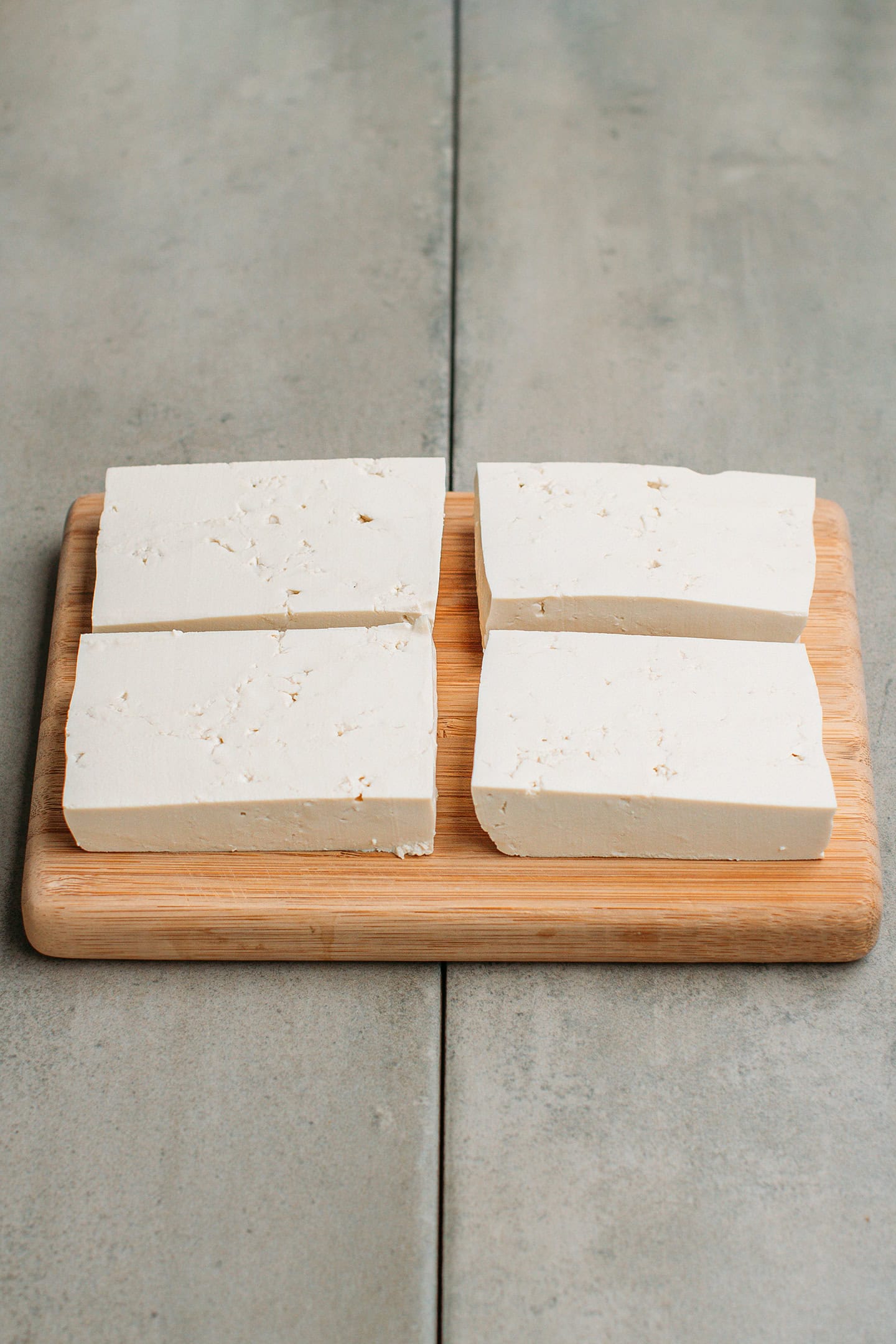 Four pieces of tofu on a cutting board.