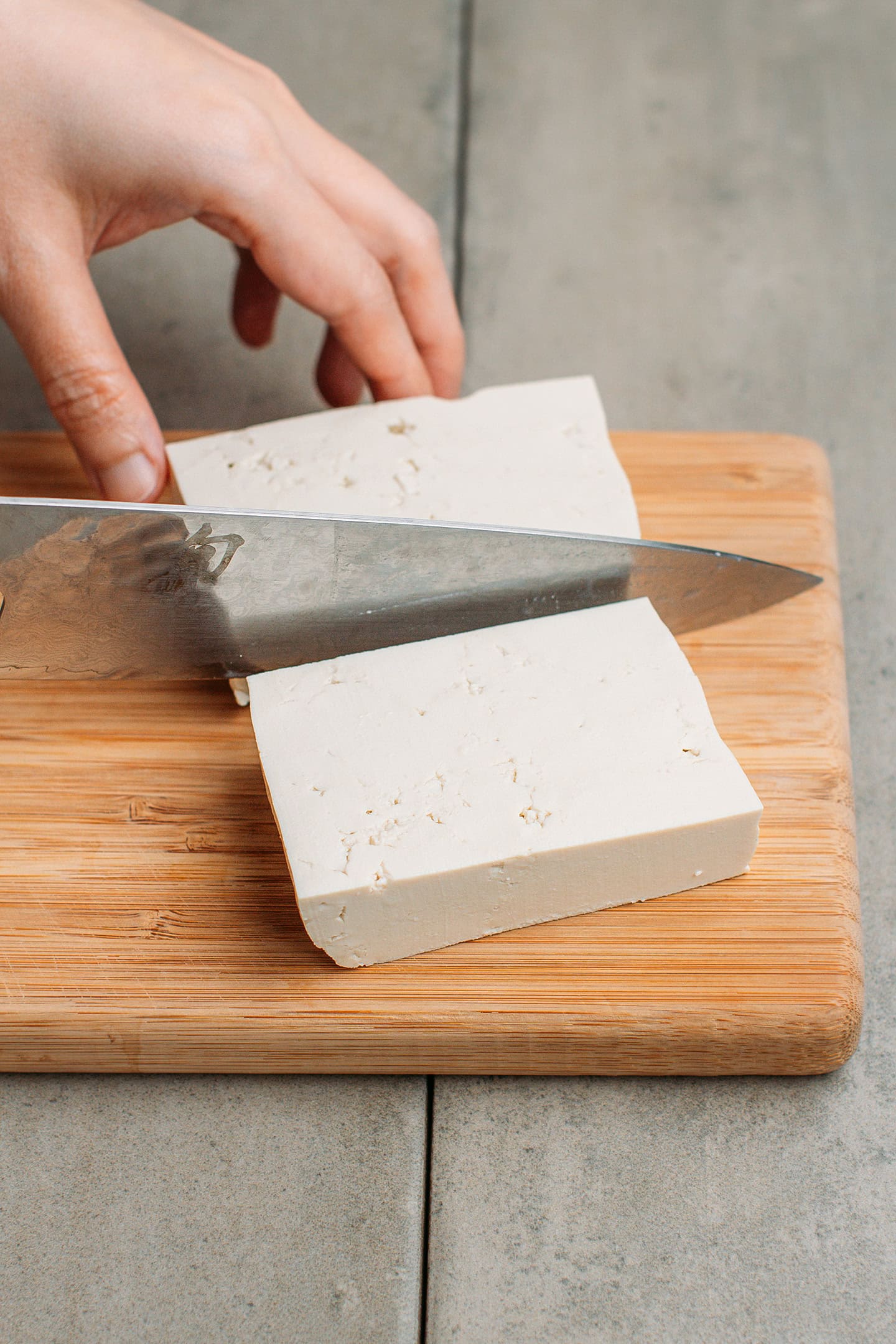 Slicing a block of tofu on a cutting board.
