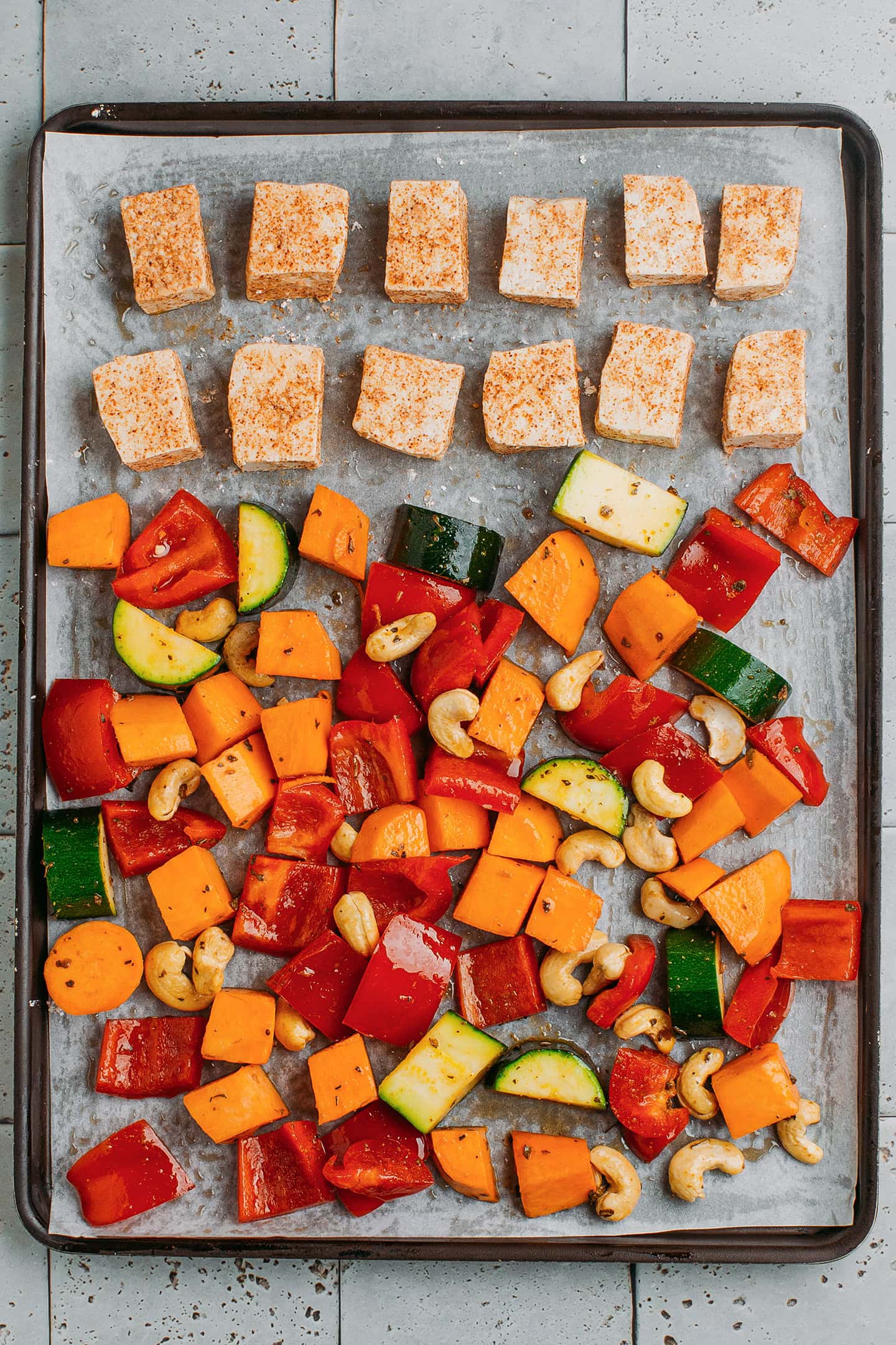 Raw vegetables and tofu on a baking sheet.