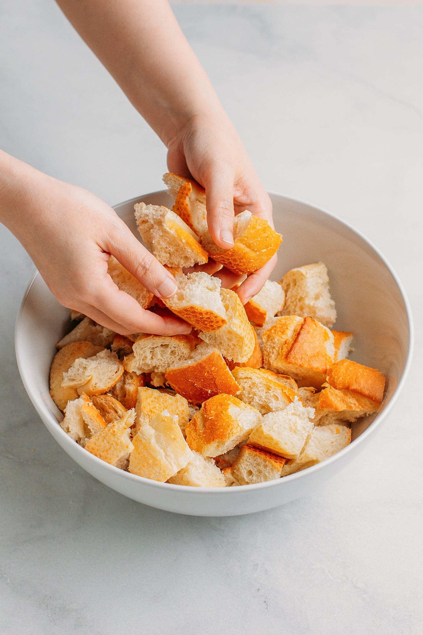 Adding diced bread to a large mixing bowl.